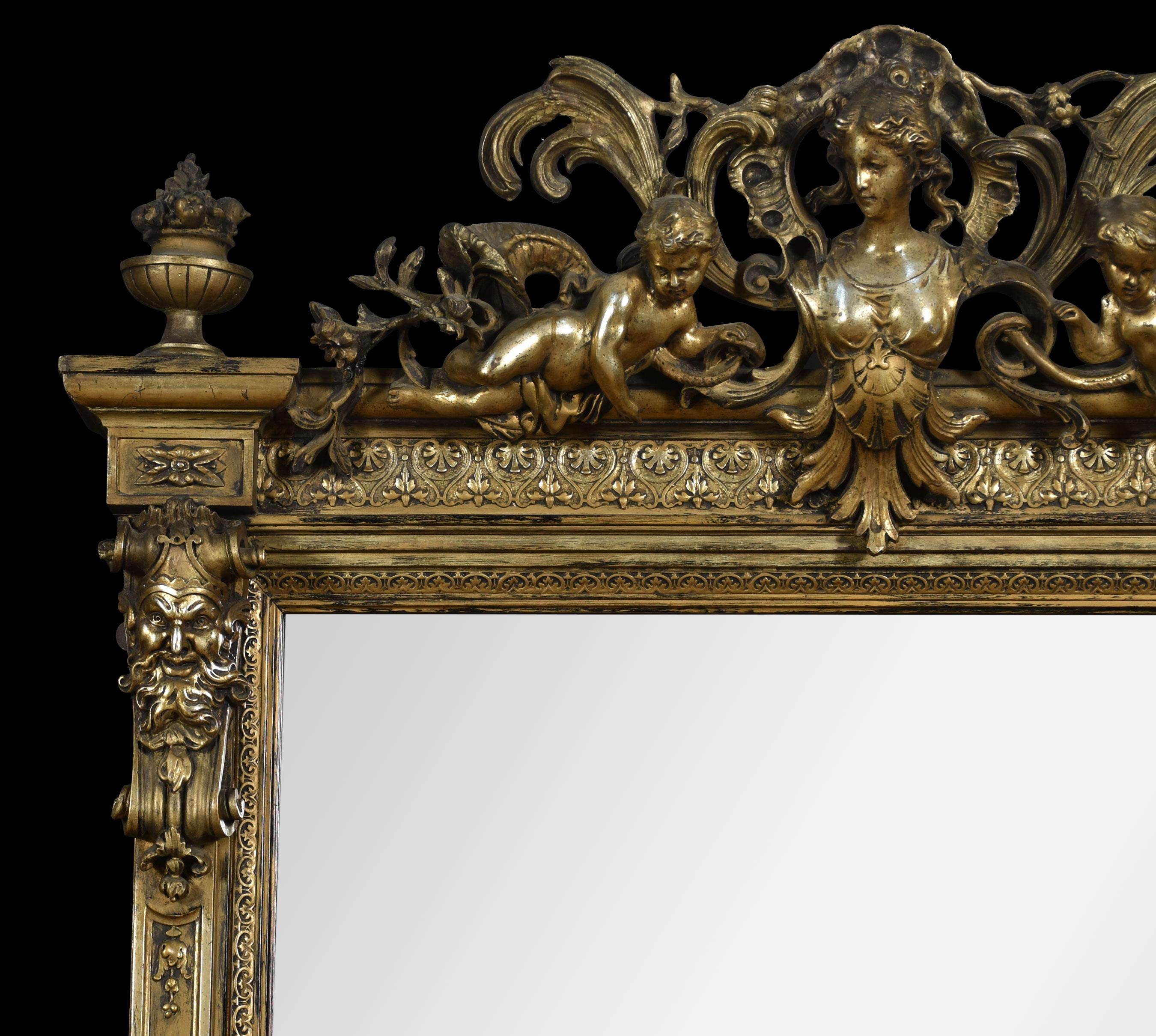 Rococo Revival giltwood and composition pier mirror. The central crest depicting Madonna with a cherub on either side and scrolling foliage flanked by urn capitals. The two columns surmounted with mystical heads above carved