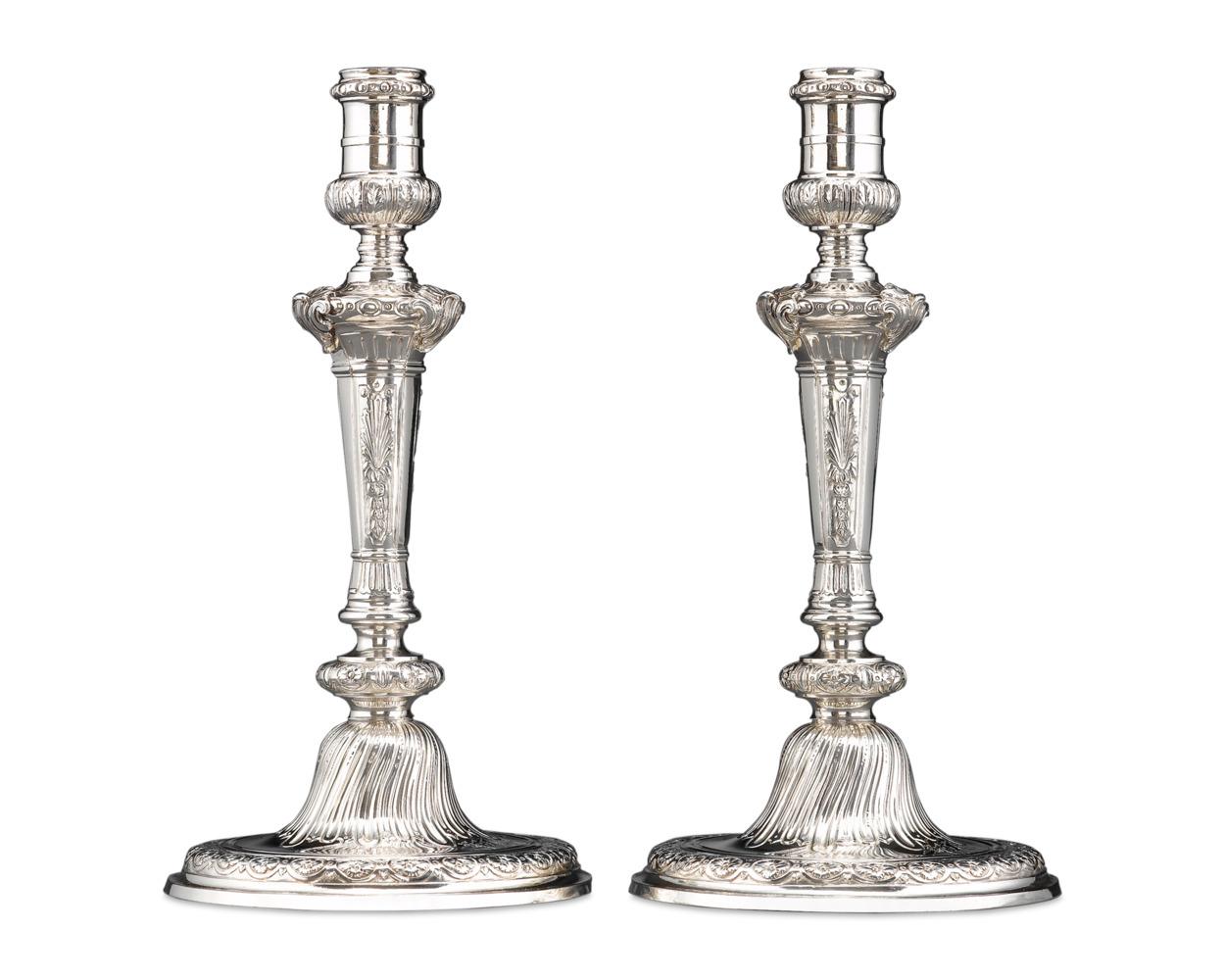 An outstanding pair of sterling silver candlesticks by English silversmith Alexander Johnston. Reflecting the mid-18th century Georgian taste for the Rococo style, these candlesticks feature deeply chased decoration, from shells and palms to