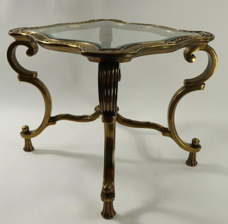 Over the top brass frame side or end table having a Rococo, or Baroque Revival style brass frame and shaped, beveled glass top. This example is in very good, clean, original, ready to use condition.
Manufacture attributed to Mastercrafters,