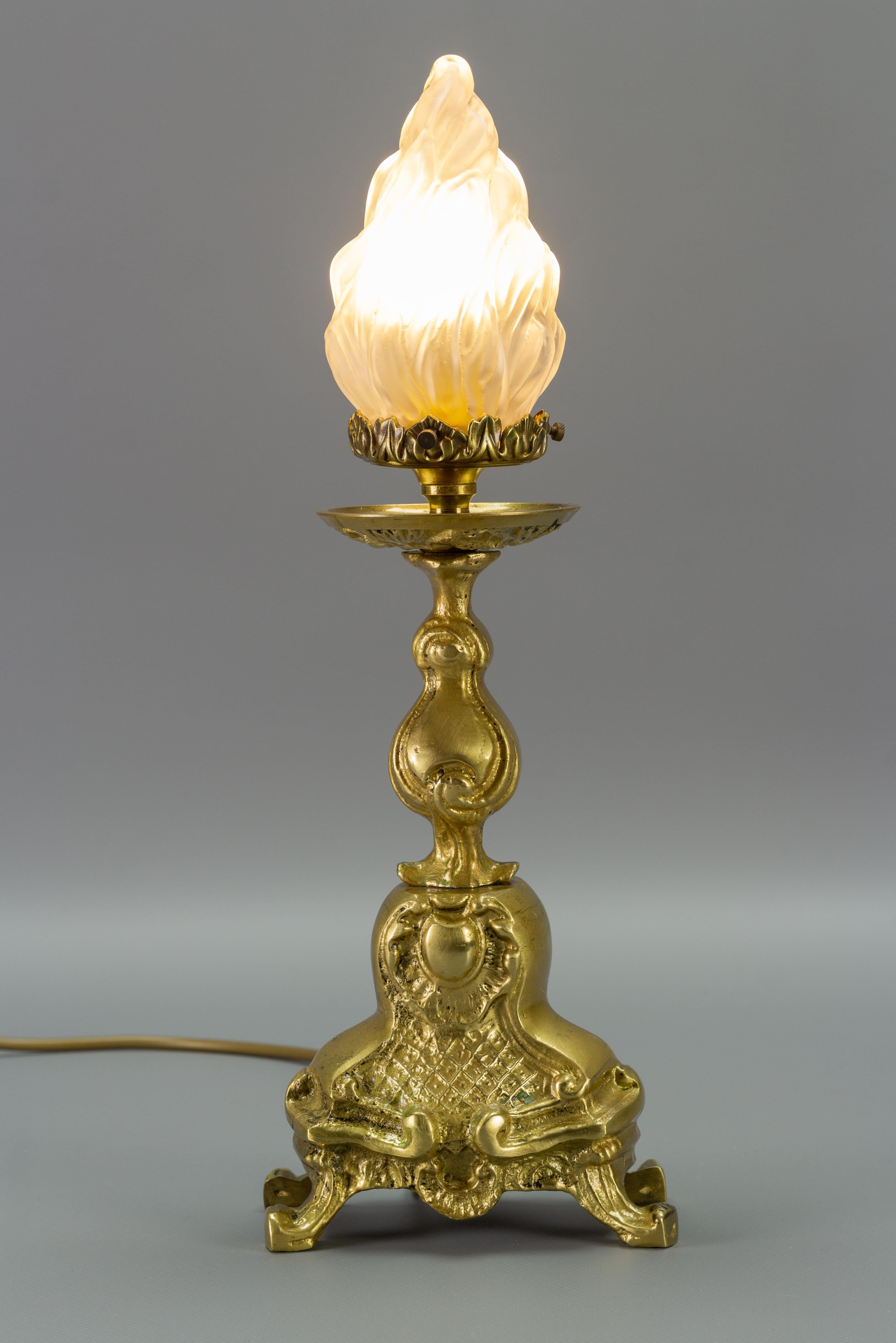 Französische Tischlampe aus Bronze im Rokoko-Stil mit flammenförmigem Lampenschirm aus Milchglas. 
Eine Fassung für eine Glühbirne der Größe E14.
In die USA werden sie mit einem Adapter für das US-Verkabelungssystem ausgeliefert.
Abmessungen: Höhe