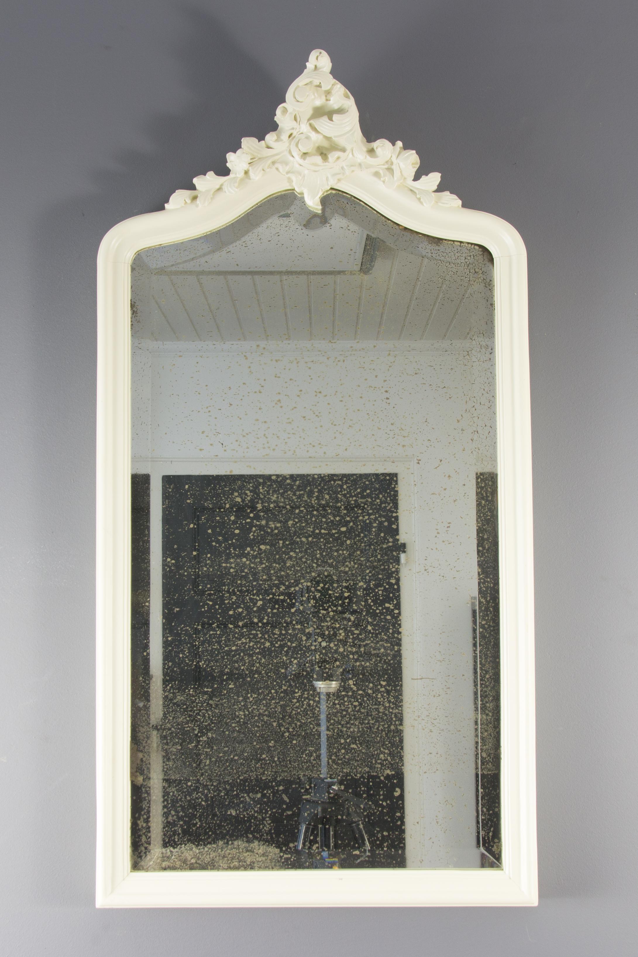 Antique French Rococo style wall mirror with ivory white newly painted oakwood frame with hand carved shell and floral details, beautifully shaped beveled mirror with nice patina.
Dimensions: Height 96 cm / 37.79 in; width 50 cm / 19.68 in; depth 6