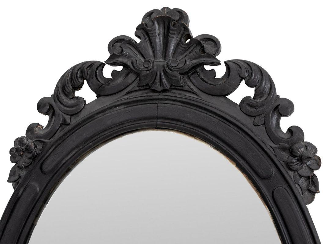 Miroir mural en bois ébonisé de style Rocaille, de forme ovale à motif de coquille rocaille. 41.5