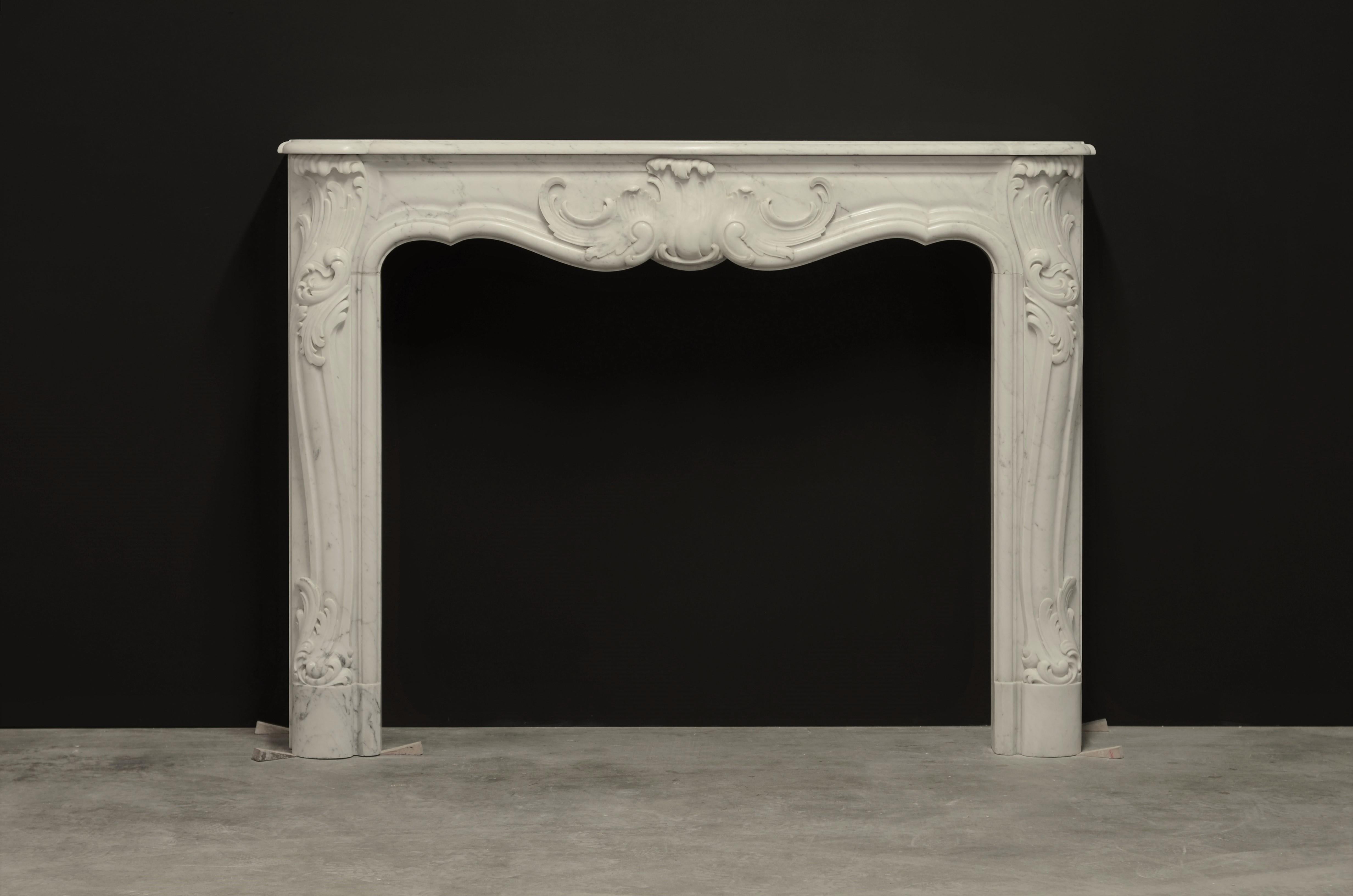 Late 19th century French Rococo revival / Louis XV style fireplace mantel.
This mantel is executed in very nice Italian Carrara white marble.

The frieze centered by a very nice a - symmetric cartouche, elegant shaped jambs with beautiful scrolls