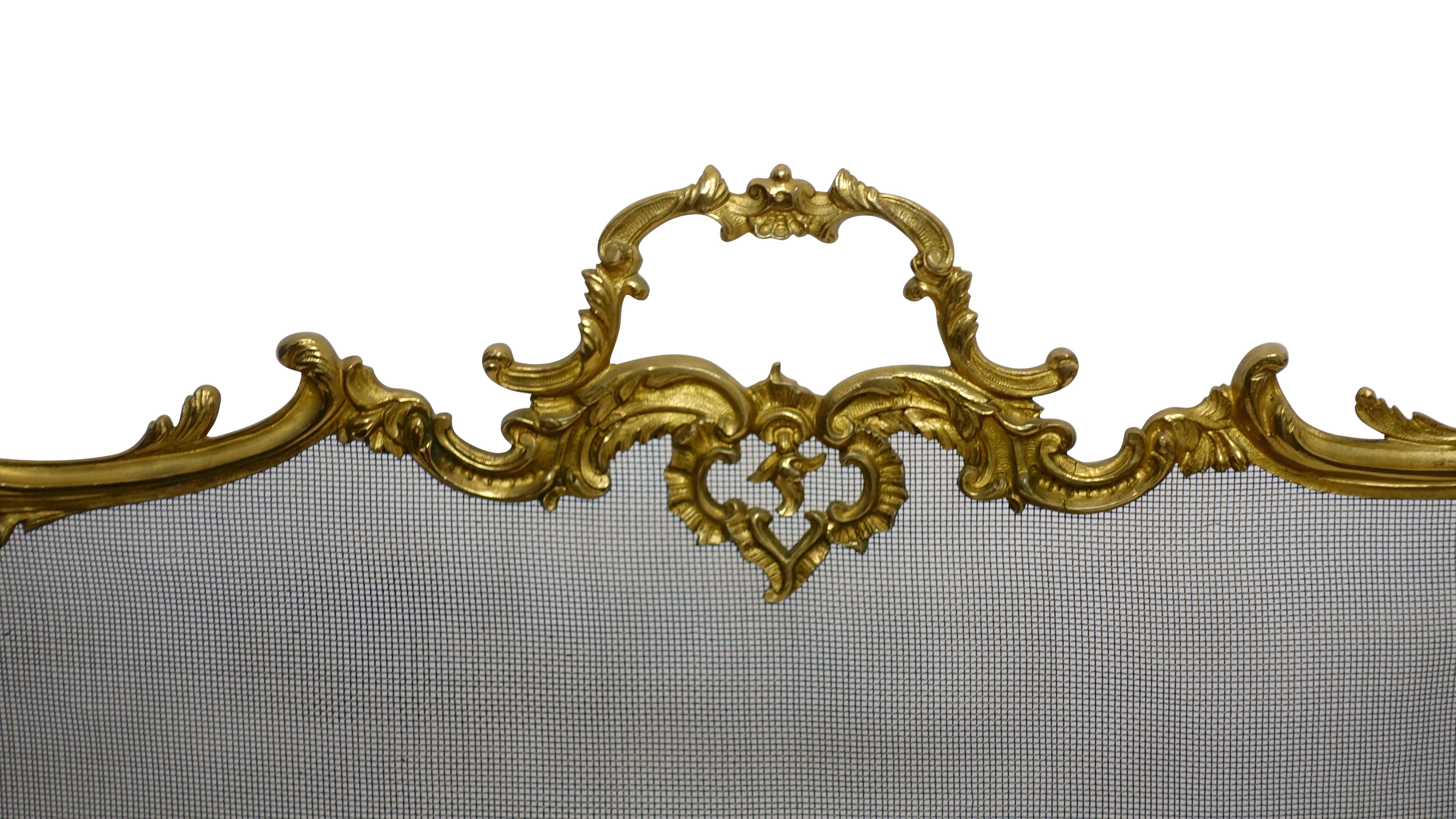 Fanciful gilt brass fireplace screen in the style of French Rococo, with C-scrolls, flowers shell shape pad feed, and a central medallion of overflowing flower basket, French, mid-20th century.