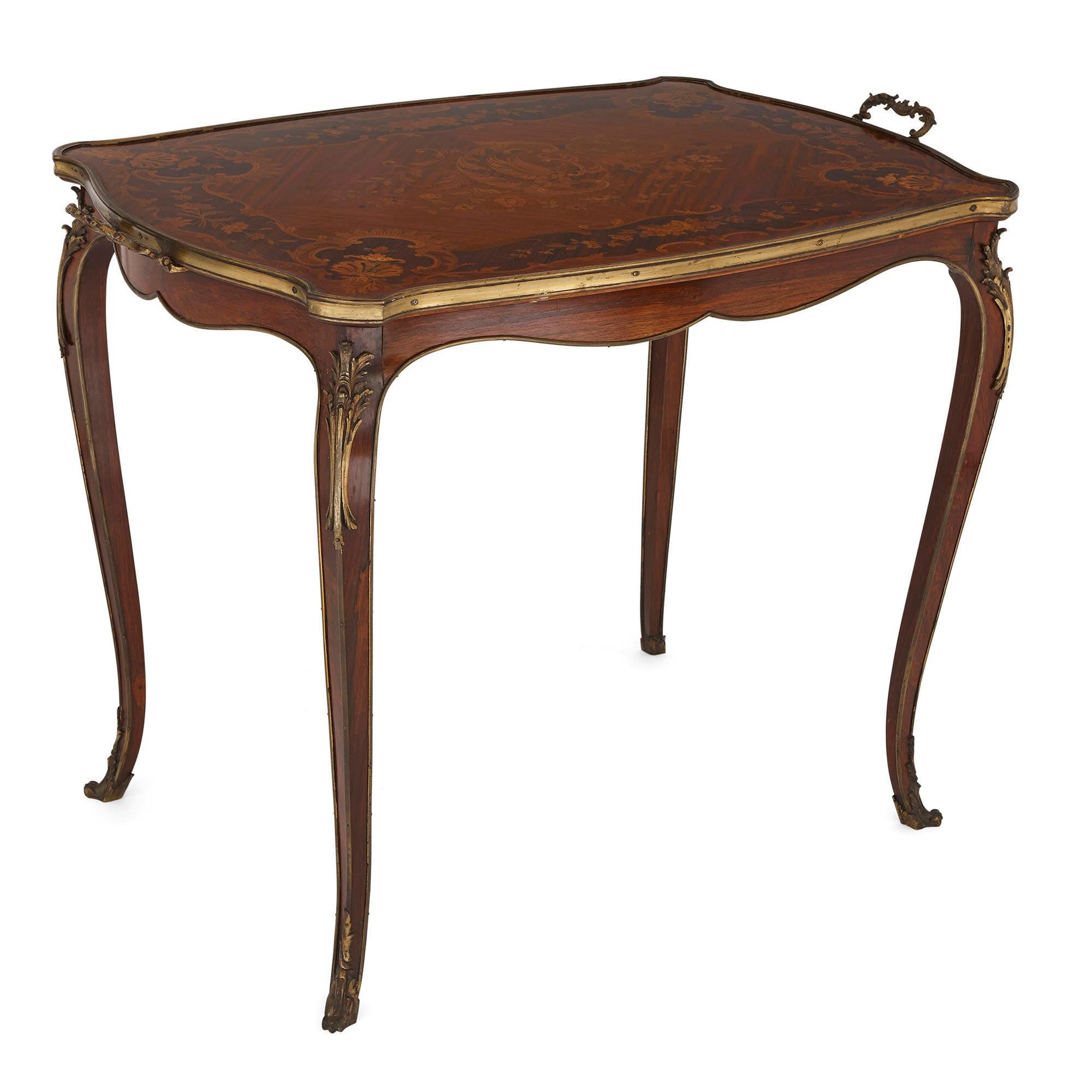 This rosewood tea table is a beautiful piece of early 20th century French furniture. It is designed in the 18th century Rococo, or Louis XV, style.

The table has a shaped rectangular top, which is exquisitely decorated with a marquetry design.