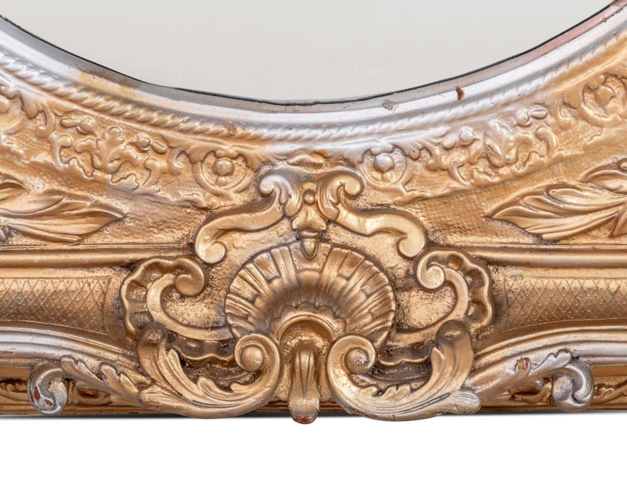 Miroir de composition de style rococo, doré et argenté, 20e siècle. Le cadre carré élaboré renferme une plaque de miroir circulaire. 34