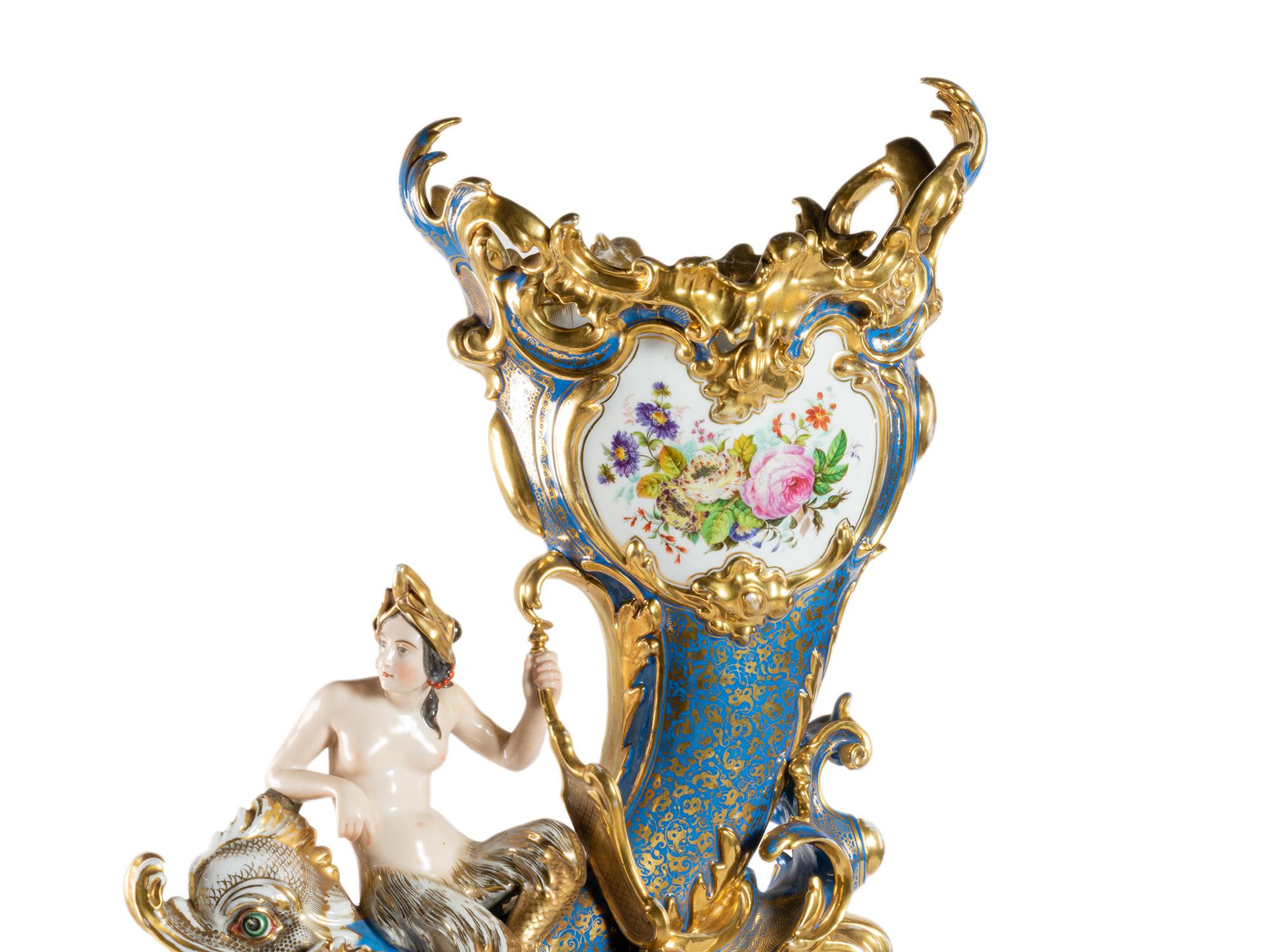 A striking vase adorned with a multicolored design depicting a dragon and a mermaid, symbolizing the mythical creature's transformation from carp to dragon. 

The background features a beautiful blue and gold hue, while the flowers add a touch of