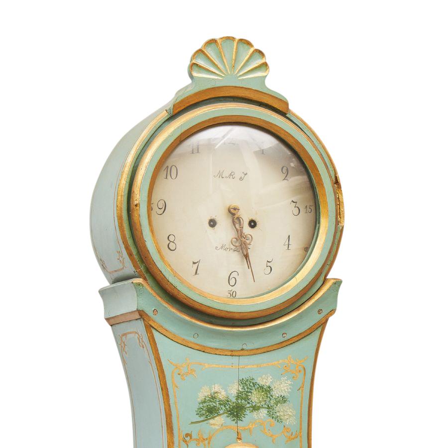 Rococo longcase Mora Clock dated 1700's with original decorative paint detailing. Face enscrobed 'M R J' 'Mora'. Carved detailing to crown. Working Longcase clock mechanism of pendulum and 2 weights and a bell chime on the hour.

Width:52cm /
