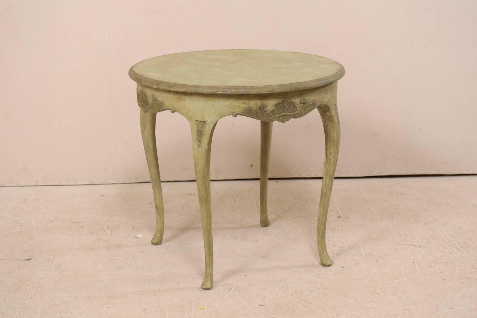 Table ronde en bois peint de style rococo suédois, datant du milieu du 20e siècle. Cette table suédoise vintage présente un plateau de forme circulaire avec un tablier joliment sculpté et légèrement festonné, orné de motifs de coquillages et de