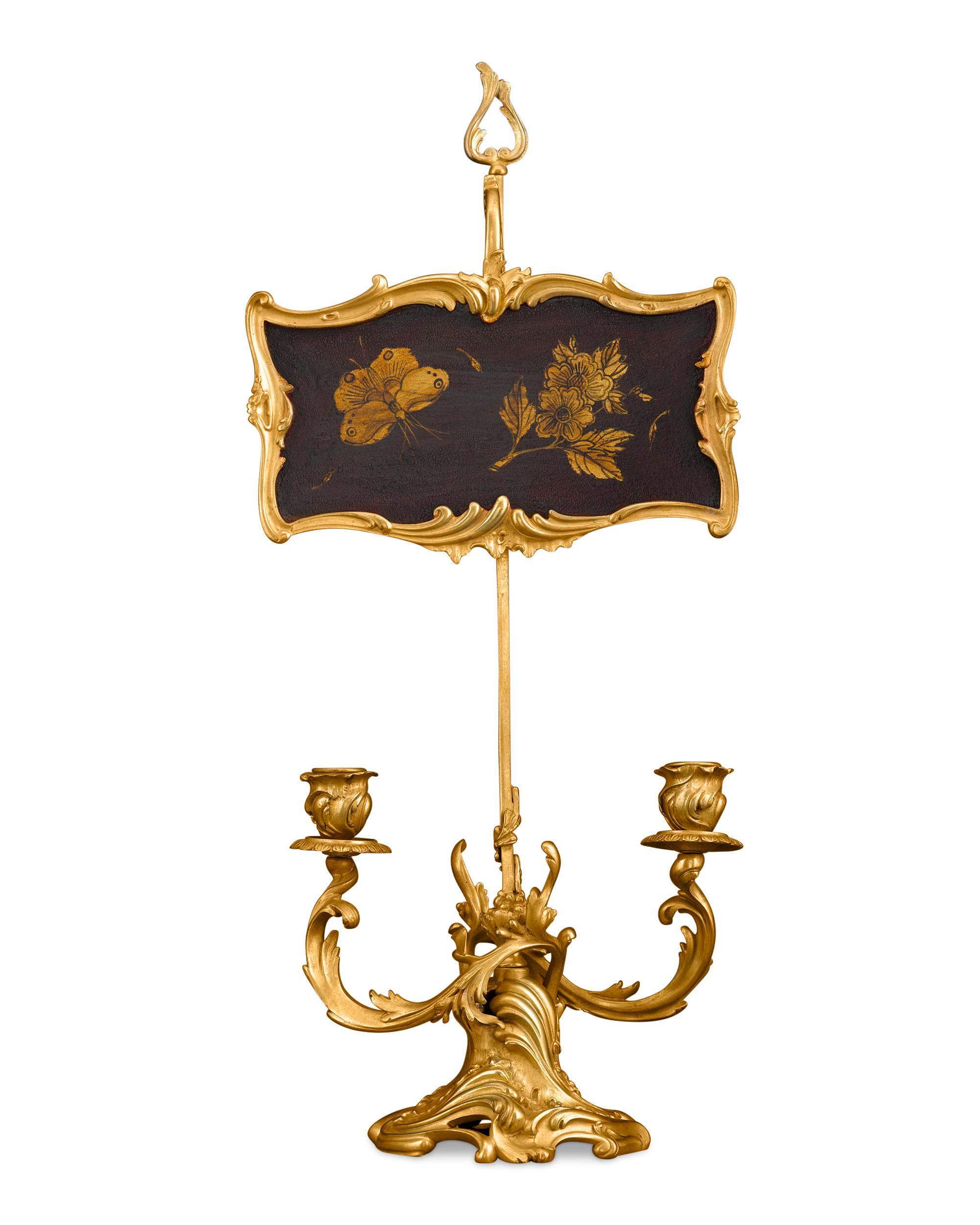 This rare and enchanting two-light candelabrum is a shining example of 19th century interior lighting. Crafted of bronze ormolu in a luxurious Rococo design, the candleholder also features a wooden screen, framed in ormolu and embellished with a