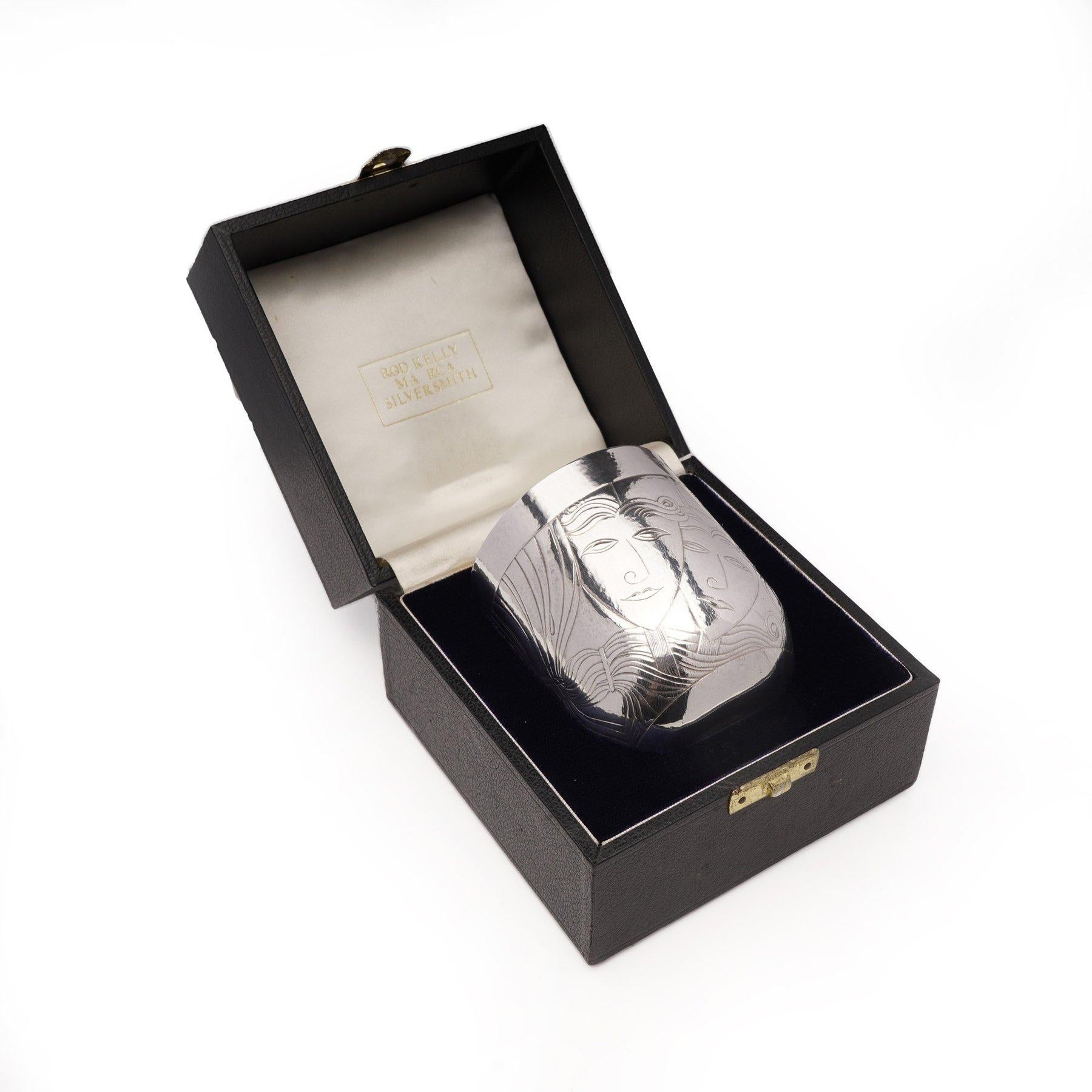 Rod Kelly MA RCA Silversmith Barclays Theatre Awards silver gilt cased beaker.

This piece features a rounded cylindrical shape adorned with finely chased decorations. It showcases Comedy and Tragedy masks, a treble clef, a tied curtain, and