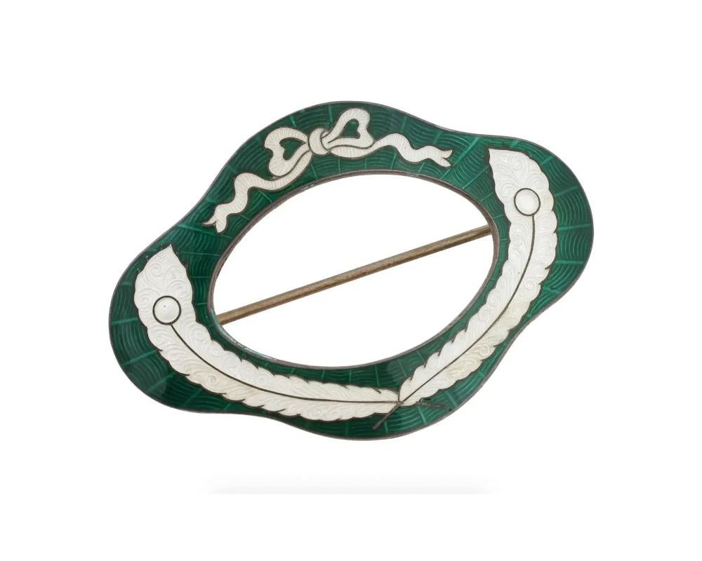 An antique gilt sterling silver pin brooch by Roden Bros Silver Ltd., a Canadian brand active from 1891 to 1953. A frame-shaped piece decorated with green and white enamel in ribbon motif. Hallmarks Sterling, 925 R, lion passant on the backside.