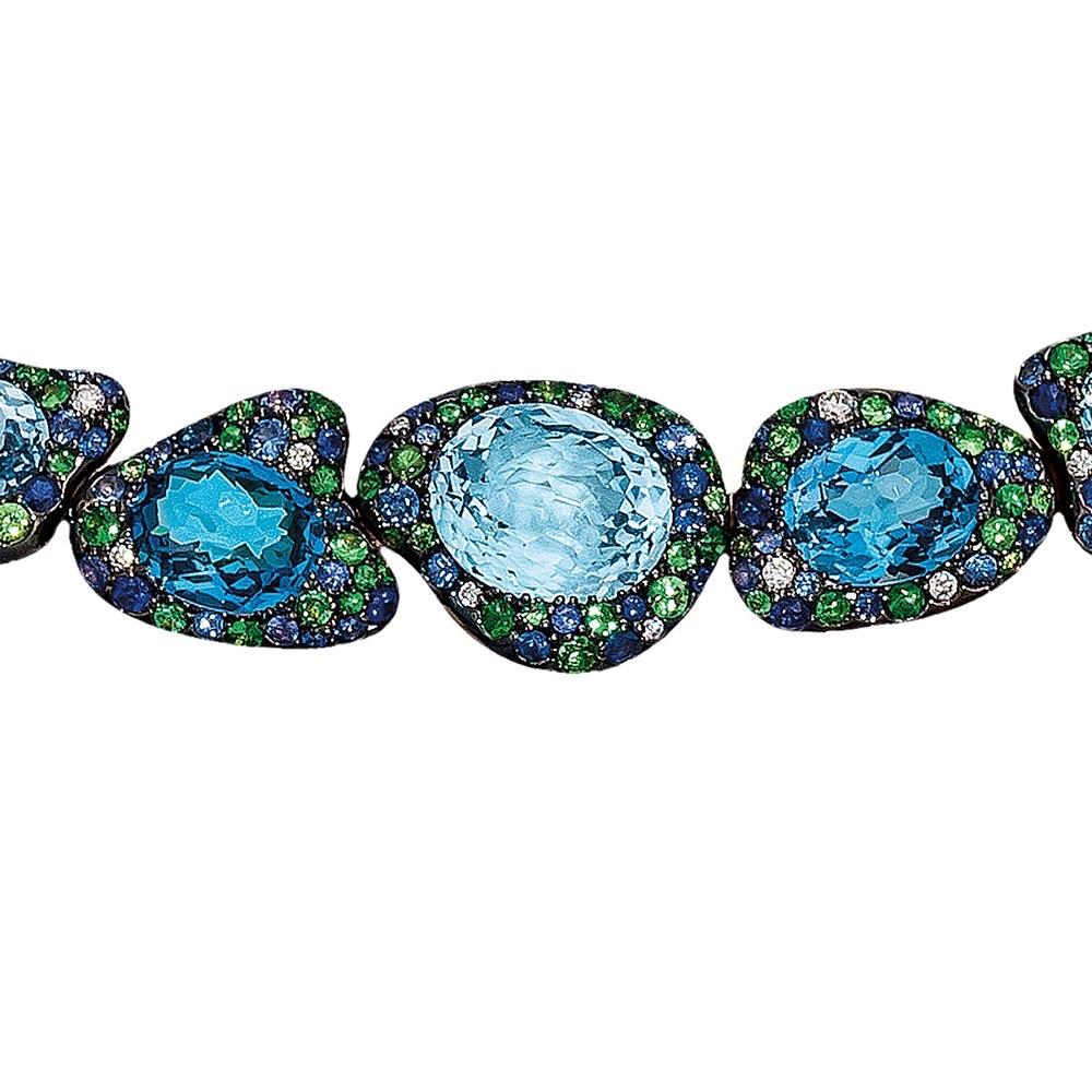 Rodney Rayner is known for his unique styling and use of beautiful color combinations. This 18 karat rose gold necklace is a perfect example of his work. Various shades of oval blue topaz stones are set in organic shaped motifs. Each center stone is
