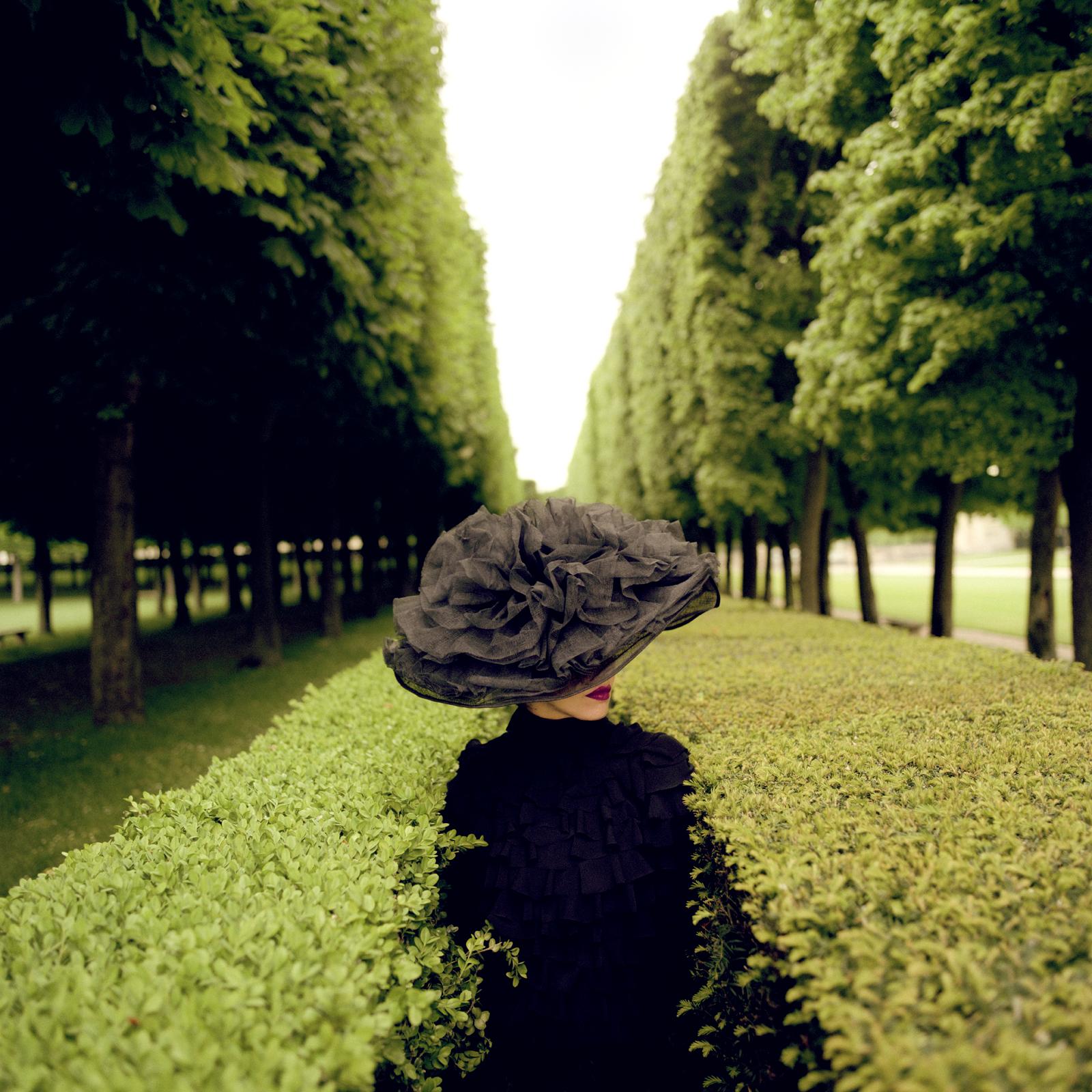 Rodney Smith Color Photograph - Woman with Hat Between Hedges, Parc de Sceaux, France - 50 x 50 inches framed