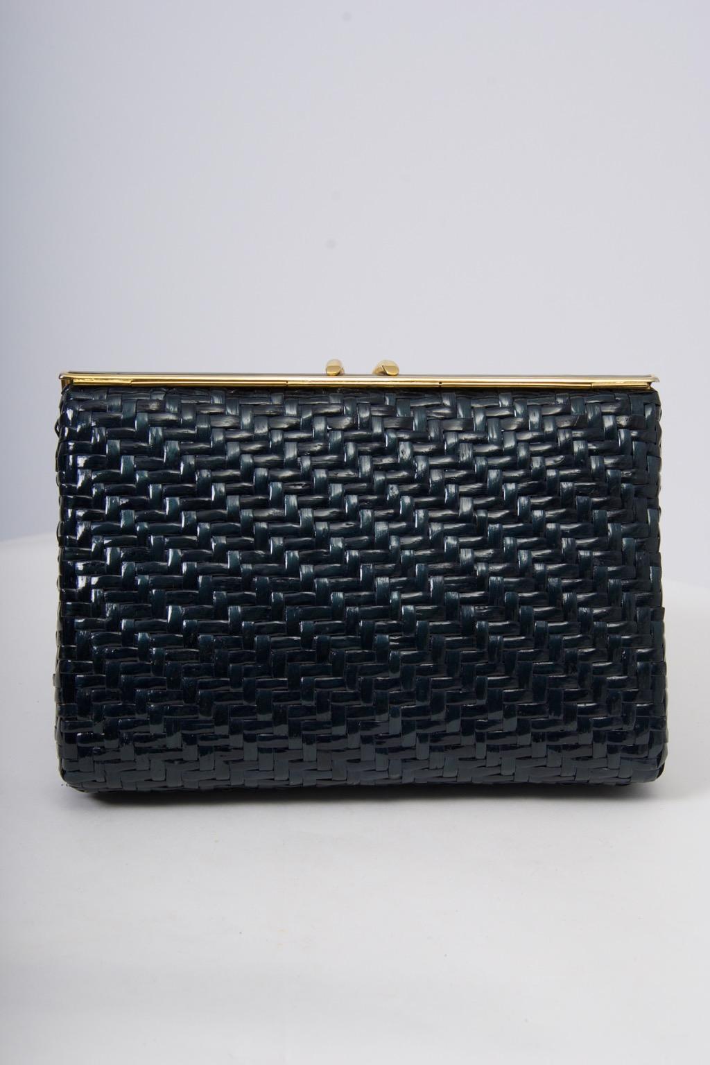 Navy wicker clutch by respected Italian company Rodo features an enameled and gold metal frame and a thin tucked-away strap that converts it into a shoulder bag. Logo interior has one side compartment.