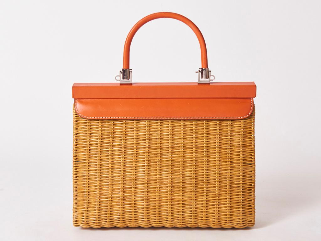 Rodo, made in Italy, rattan and orange tone leather handbag. Upper part of the bag is leather including the top handle . The closure is magnetic. Body of the bag is rattan. Interior is lined in khaki canvas with a zippered compartment. 