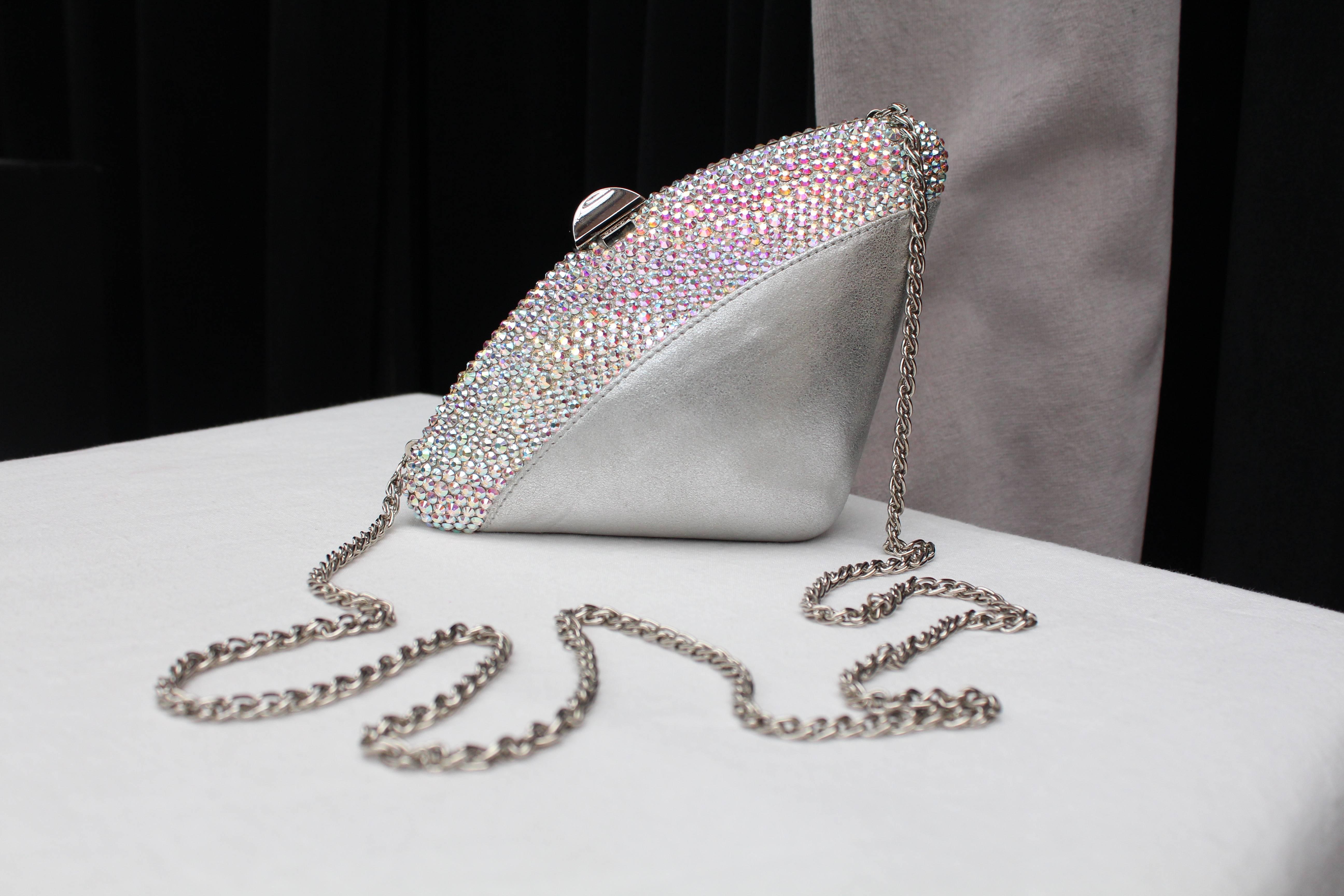 RODO (Made in Italy) Small triangular evening bag composed of silvery leather decorated with sequins. It opens with a push button closure made of silver tone metal stamped with the brand name. Silvery leather lining. It can be worn over the shoulder