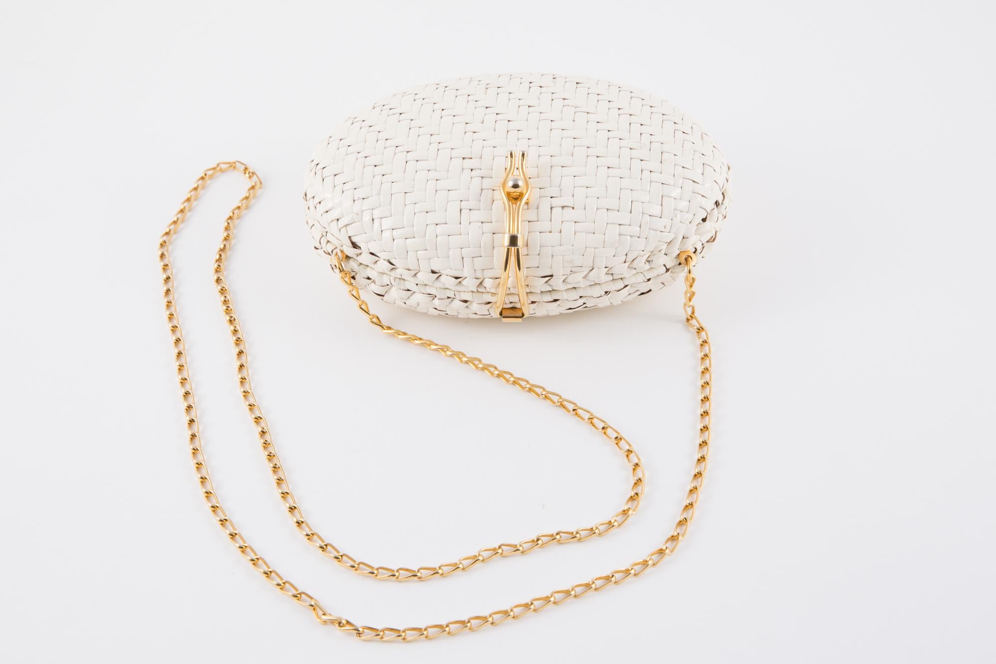 1970s, white Rodo clutch bag featuring a white patent woven wicker, a gold-tone front claps closure, a gold-tone chain shoulder strap (43.3 in. (110cm)), a logo lining. 
Made in Italy.
In good vintage condition ( Some holes in the inside