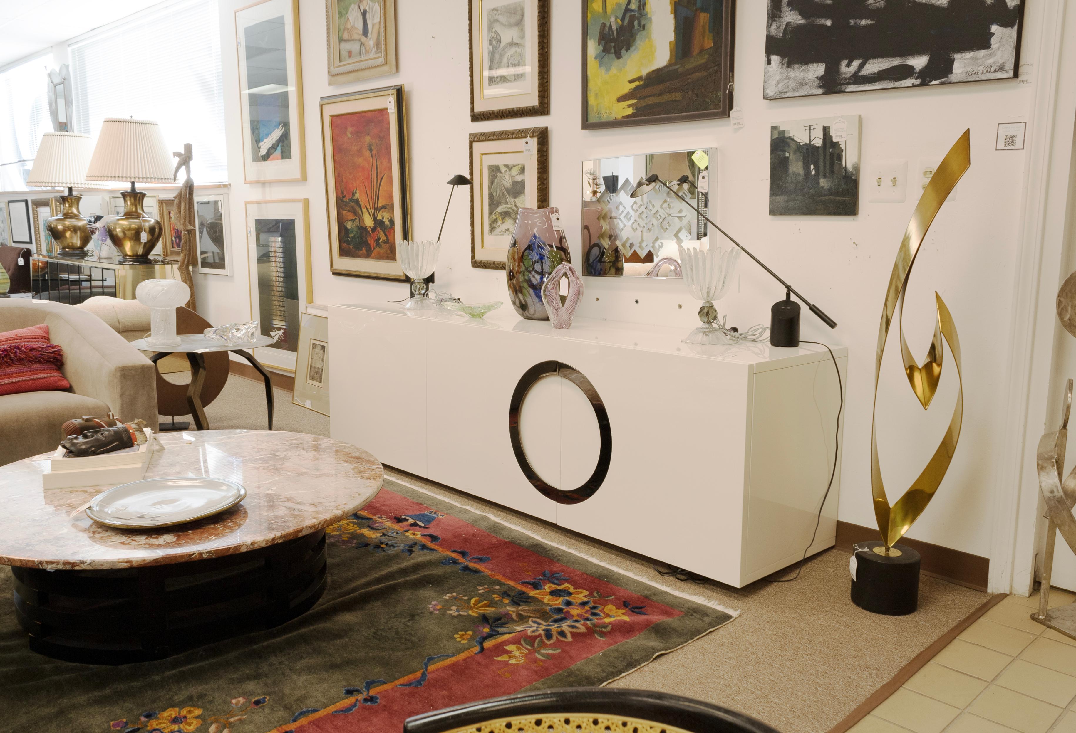 An Archipenko credenza cabinet designed by Rodolfo Dordoni for Minotti. This gorgeous contemporary modern cabinet features a clean, white lacquered exterior with a circular chrome design accent across the doors. This piece features 3 large cabinet