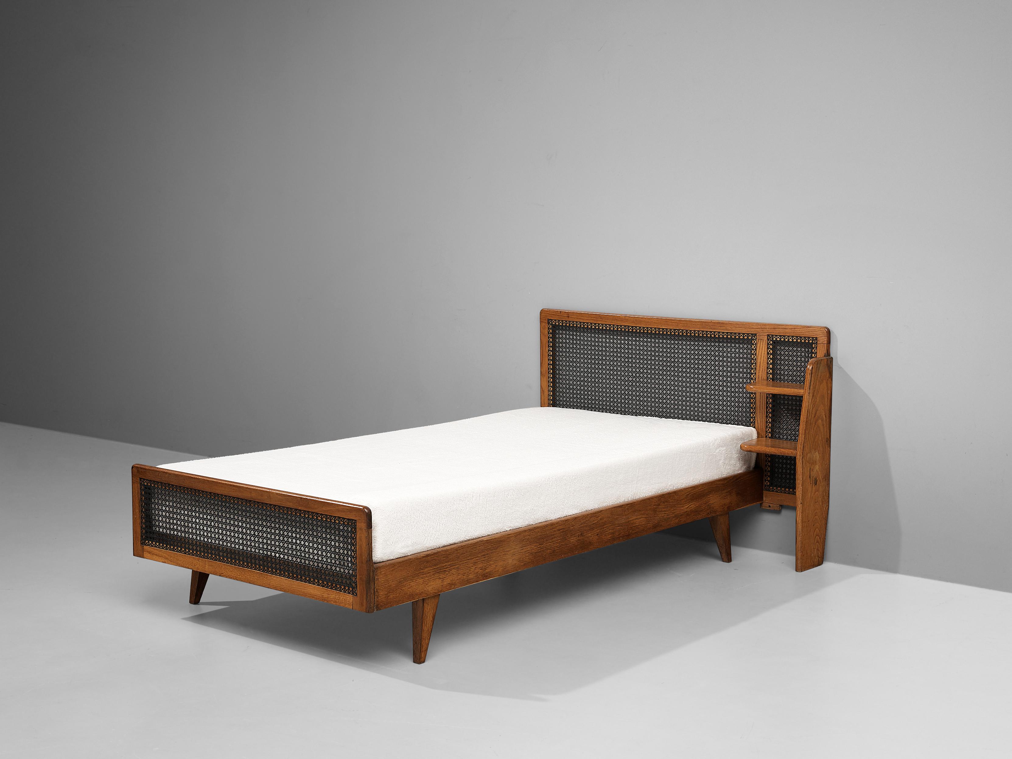 Roger Landault, single bed, oak and cane, France, 1950s

French Post-War Reconstruction single bed designed by Roger Landault. The bed is made of oak and features a headboard and footboard decorated with cane. Shelving forms an integrated nightstand