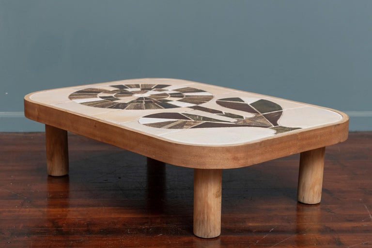 Roger Capron design ceramic coffee table, France. Lovely and colorful floral motif top enclosed by a banded fruitwood top on cylindrical legs, signed.