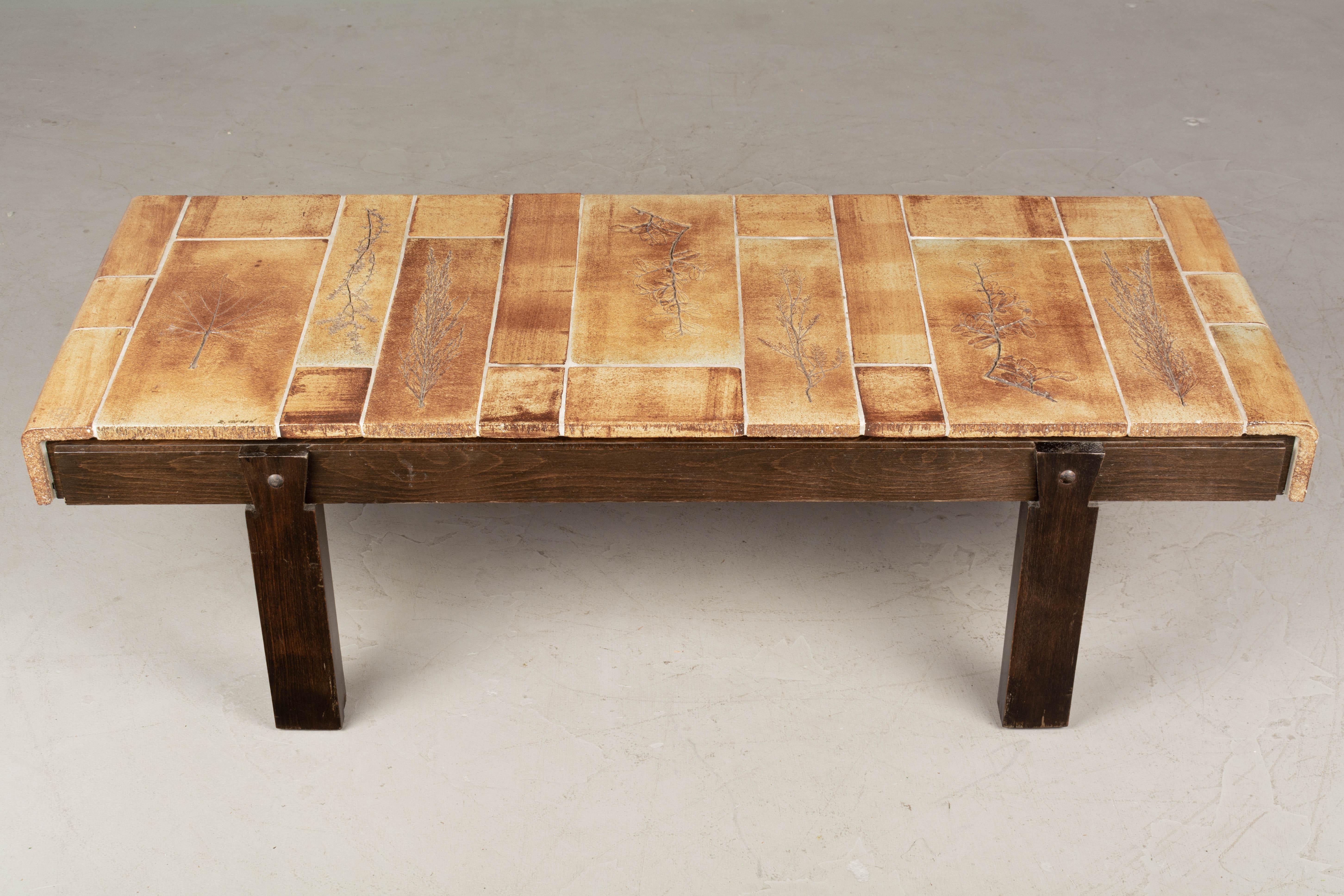 A Roger Capron coffee table from his Garrigue series with a solid oak base and a top made of finely crafted earthenware ceramic tiles imprinted with various plant specimens to look like fossils. Garrigue refers to the vegetation that grows wild on