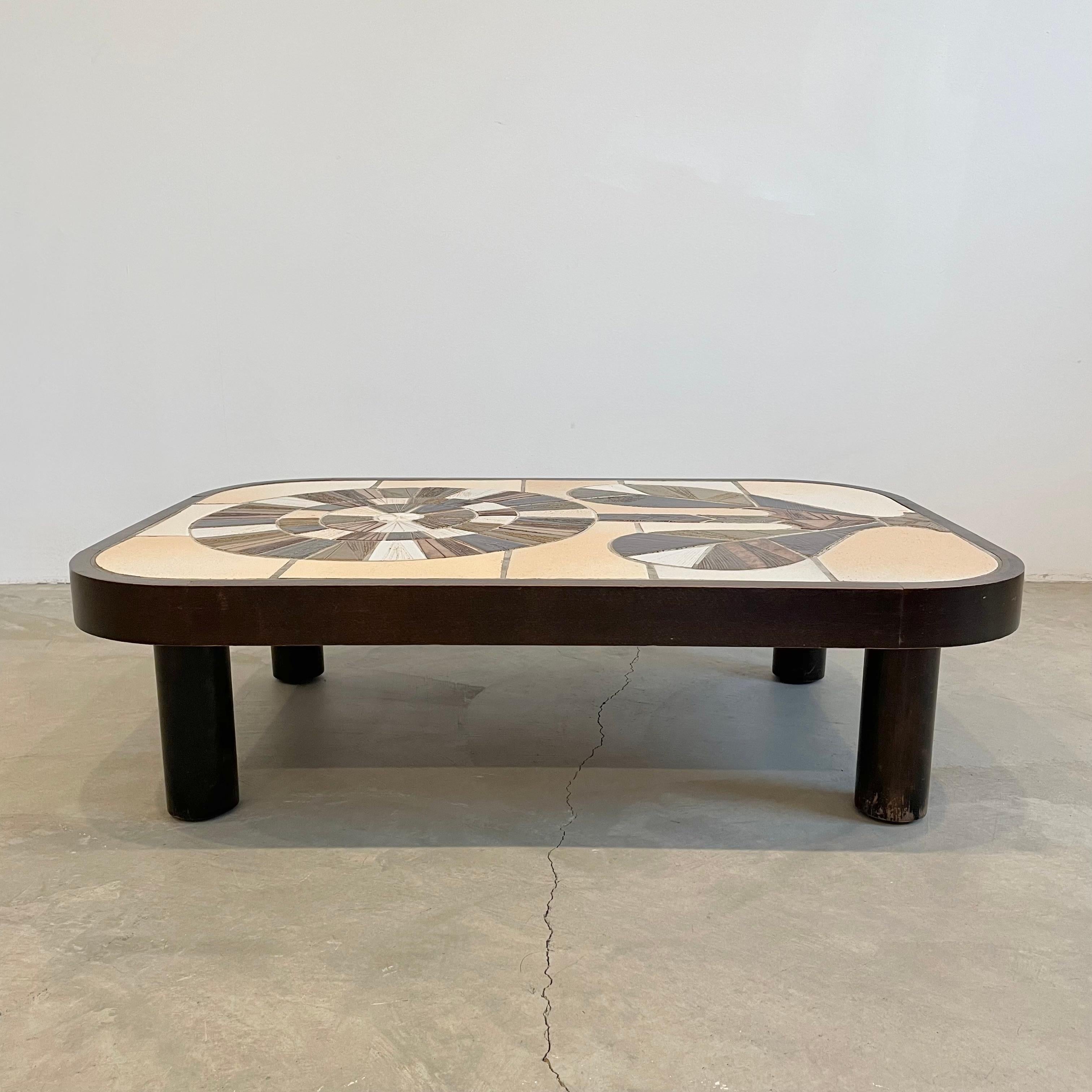 Magnifique table basse française avec des carreaux de céramique composés de manière complexe par l'artiste céramiste français Roger Capron. Il présente un motif vibrant d'une fleur créée par des carreaux de couleurs différentes s'inspirant du