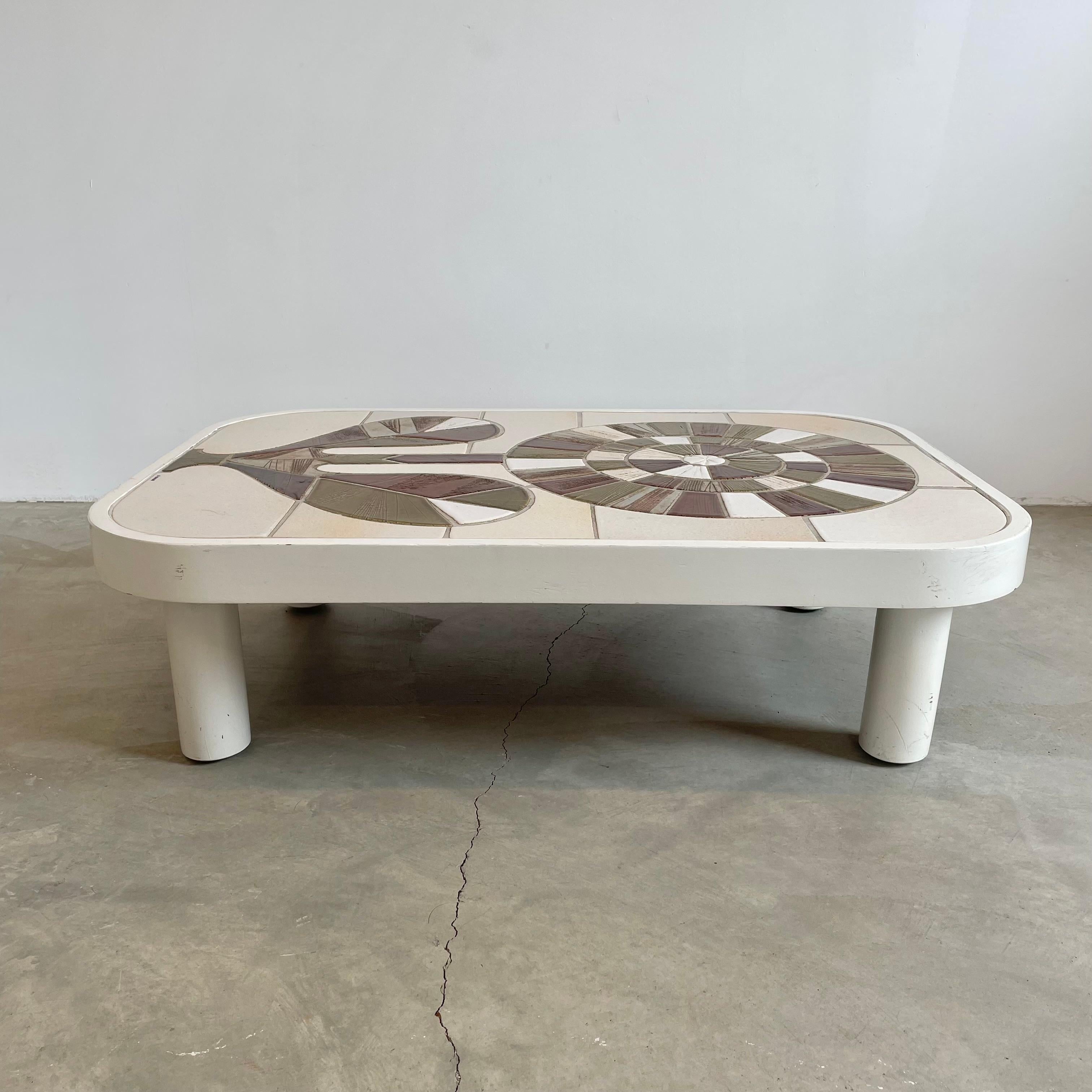 Beautiful French coffee table with intricately composed ceramic tiles by French ceramic artist Roger Capron. It features a vibrant motif of a flower created by differently colored tiles drawing inspiration from Scandinavian modernism.
