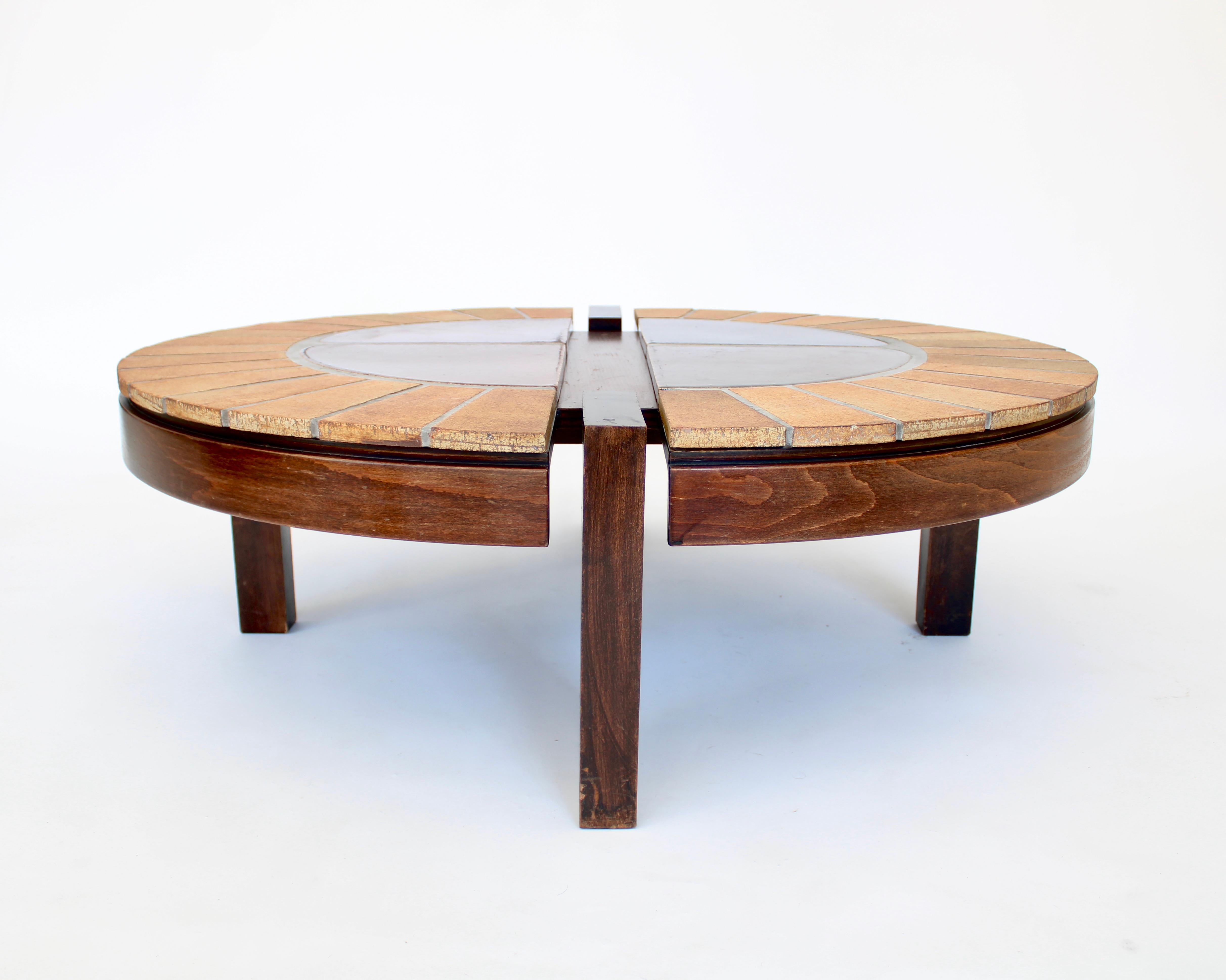 Roger Capron oval French ceramic coffee table with dark stained walnut wood understructure. 
Four large brown glazed center panels surrounded by radiating unglazed tiles with a warm tone to the tiles
Signed R Capron.
Made in Vallauris, France