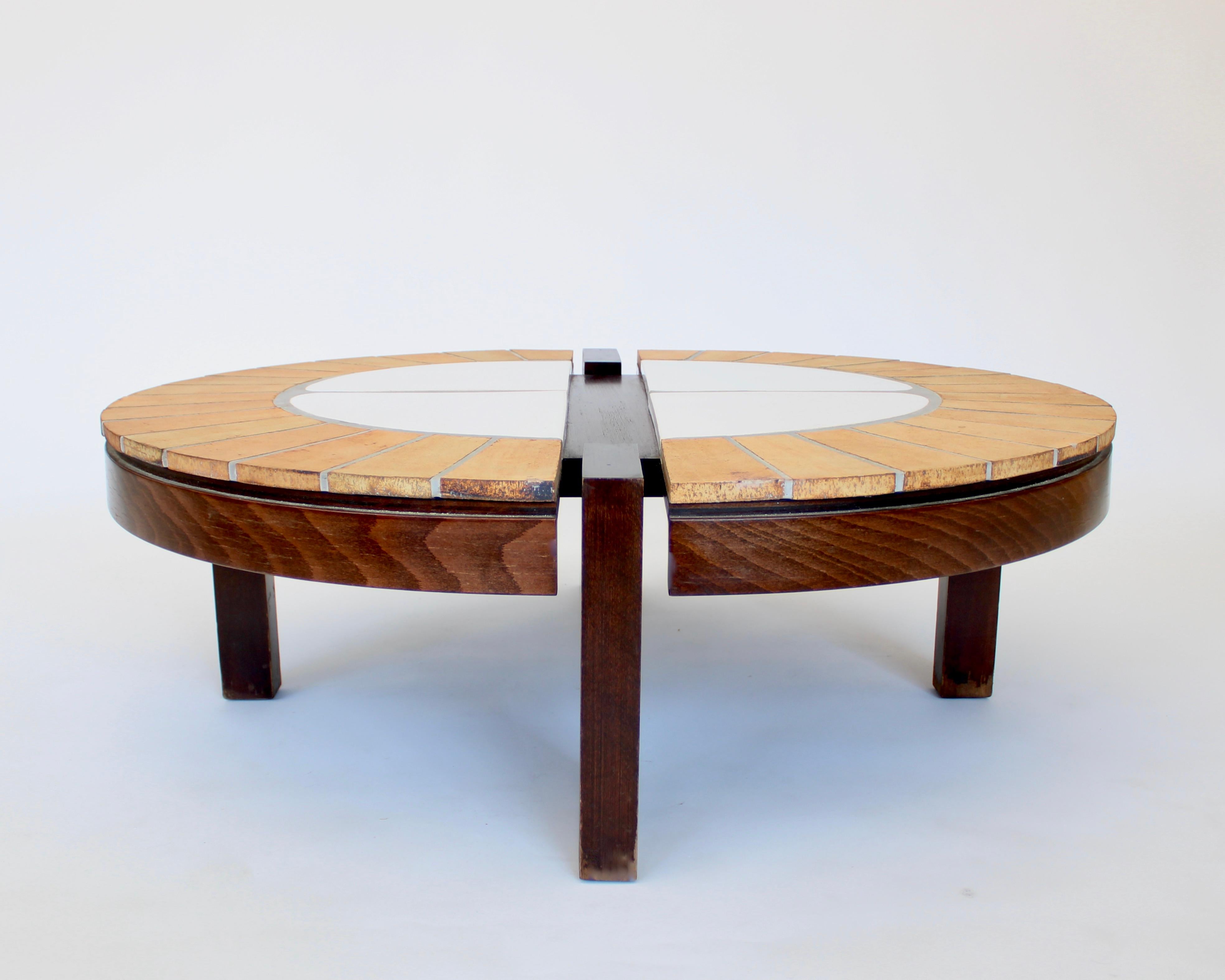 Table basse ovale en céramique française de Roger Capron avec structure en bois de noyer teinté foncé. 
Quatre grands panneaux centraux émaillés blancs entourés de carreaux non émaillés rayonnants aux tons chauds.
Signé R. Capron.
Fabriqué à