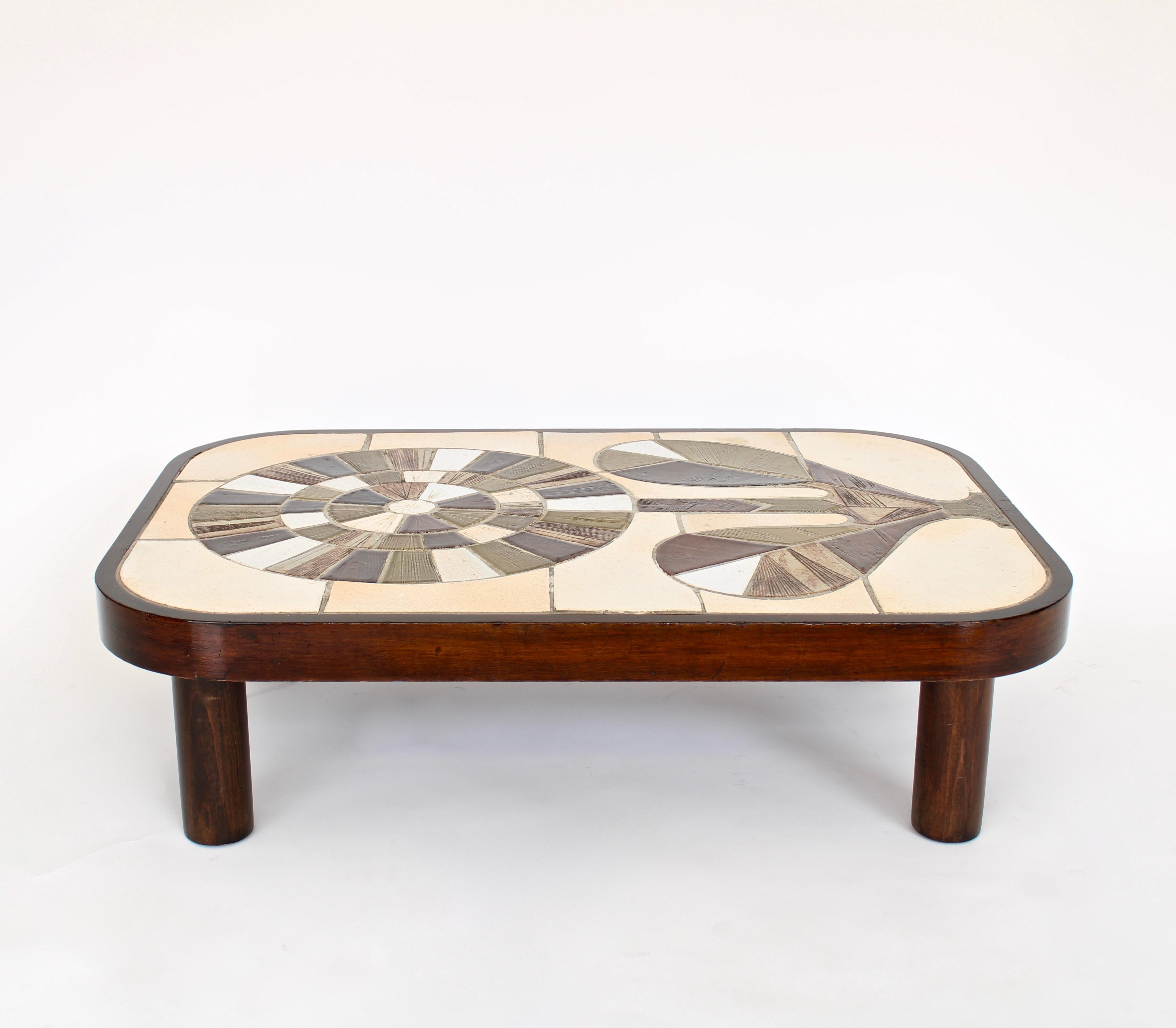 Roger Capron French ceramic handmade tiled coffee table with a vibrant radiating sunflower motif. 
Colors of olive green and shades of olive green and brown, tan, beige and white. 
All the grouting is in place. The wood frame has a dark stain and