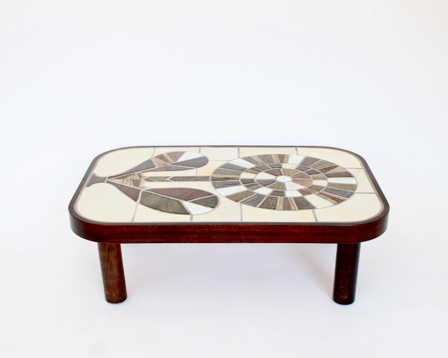 Table basse en céramique française de Roger Capron avec un vibrant motif de tournesol rayonnant. 
Couleurs vert olive et nuances de vert olive et de brun, de tan, de beige et de blanc. 
Tous les joints sont en place. Le cadre en bois est teinté en