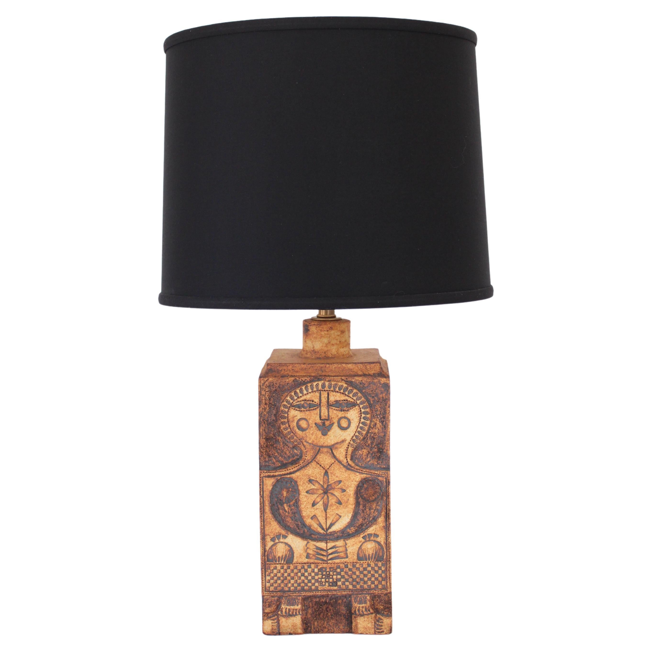 Lampe de table de l'artiste céramiste français Roger Capron. La lampe est dessinée avec l'image de la femme que Capron utilisait très souvent. Souvent souriant, avec le soleil ou un motif floral dans l'image. L'argile est appelée Gres, une argile