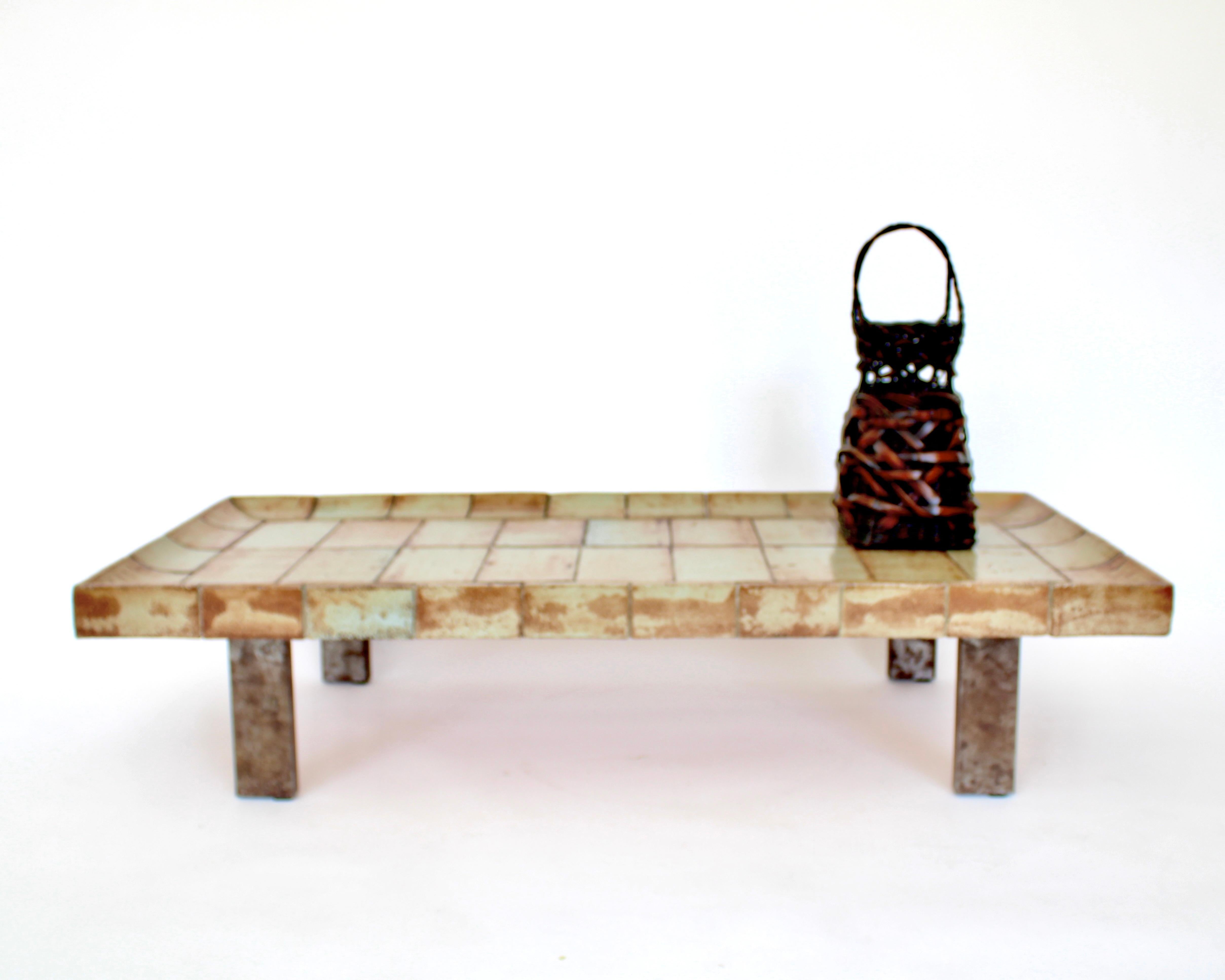 Roger Capron French ceramic tile coffee table model Cuvette. 
This table is composed of tiles that each exhibit the strong influence of the fire in the kiln and vary in colors of warm light browns and tan. 
The tiles have a central motif of two rows