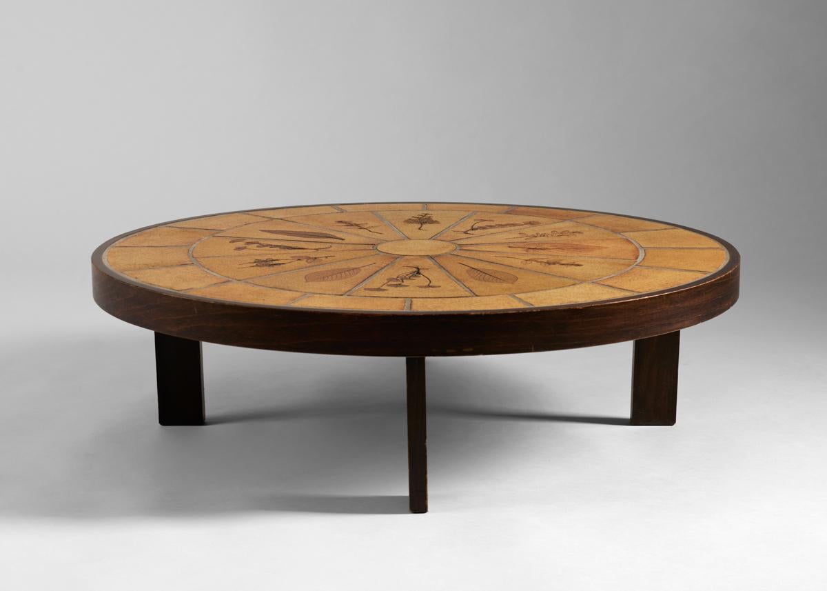 A coffee table with a simple, elegant, iron base, and a top of rectangular
tiles punctuated by beautifully inscribed images of foilage.