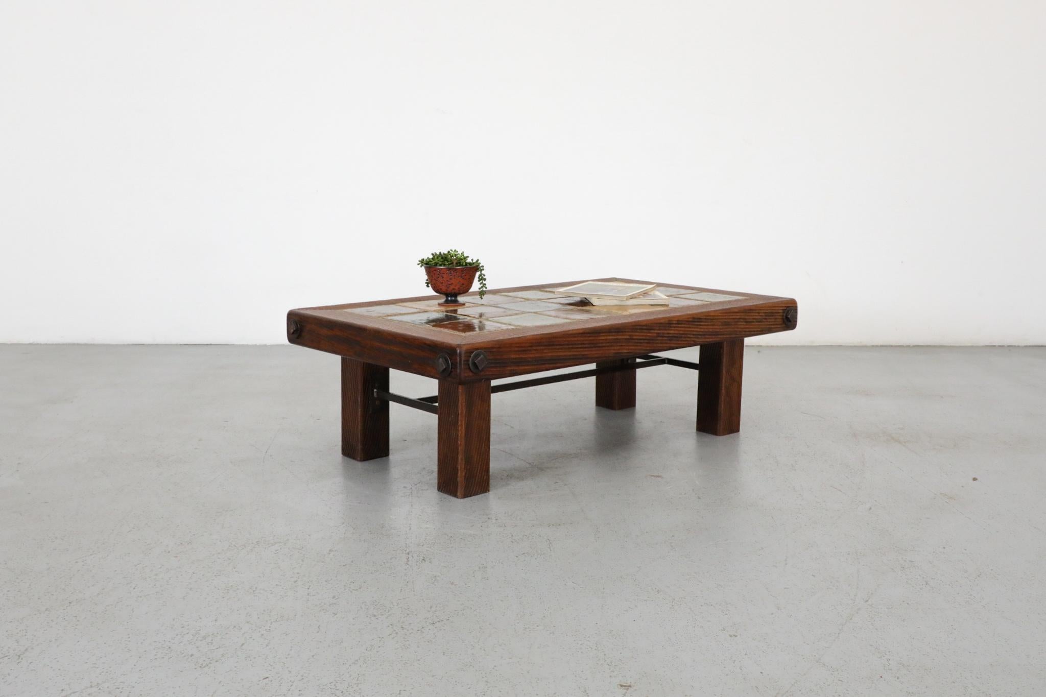 Brutalist grooved oak and tile coffee table inspired by Roger Capron. Heavy oak framed top, with multi-color square inset ceramic tiles in excellent 70s palette. Sits on thick square oak legs with black enamel metal trestle supports. In original