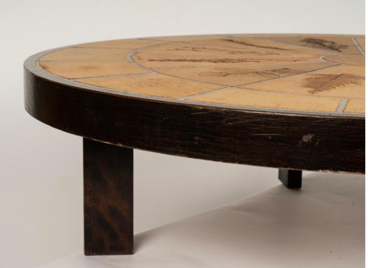 Roger Capron (1922 - 2006): Oval Coffee Table
Vallauris, France; 1970s; ceramic tile with botanical motifs, stained wood; impressed to tile 