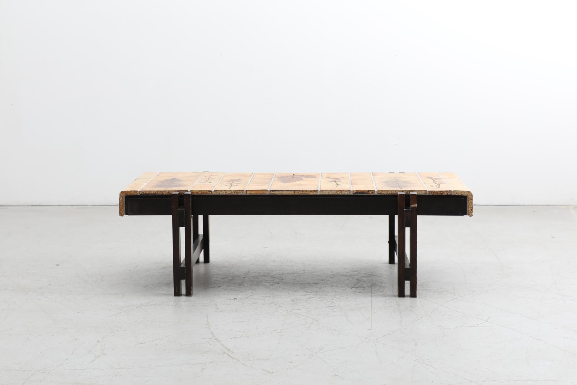 La table basse 'Garrigue' de Roger Capron présente un cadre architectural délicat en bois et des carreaux de céramique à feuilles pressées provenant de Vallauris, en France. Pour créer un thème organique sur les carreaux, Capron y a imprimé des