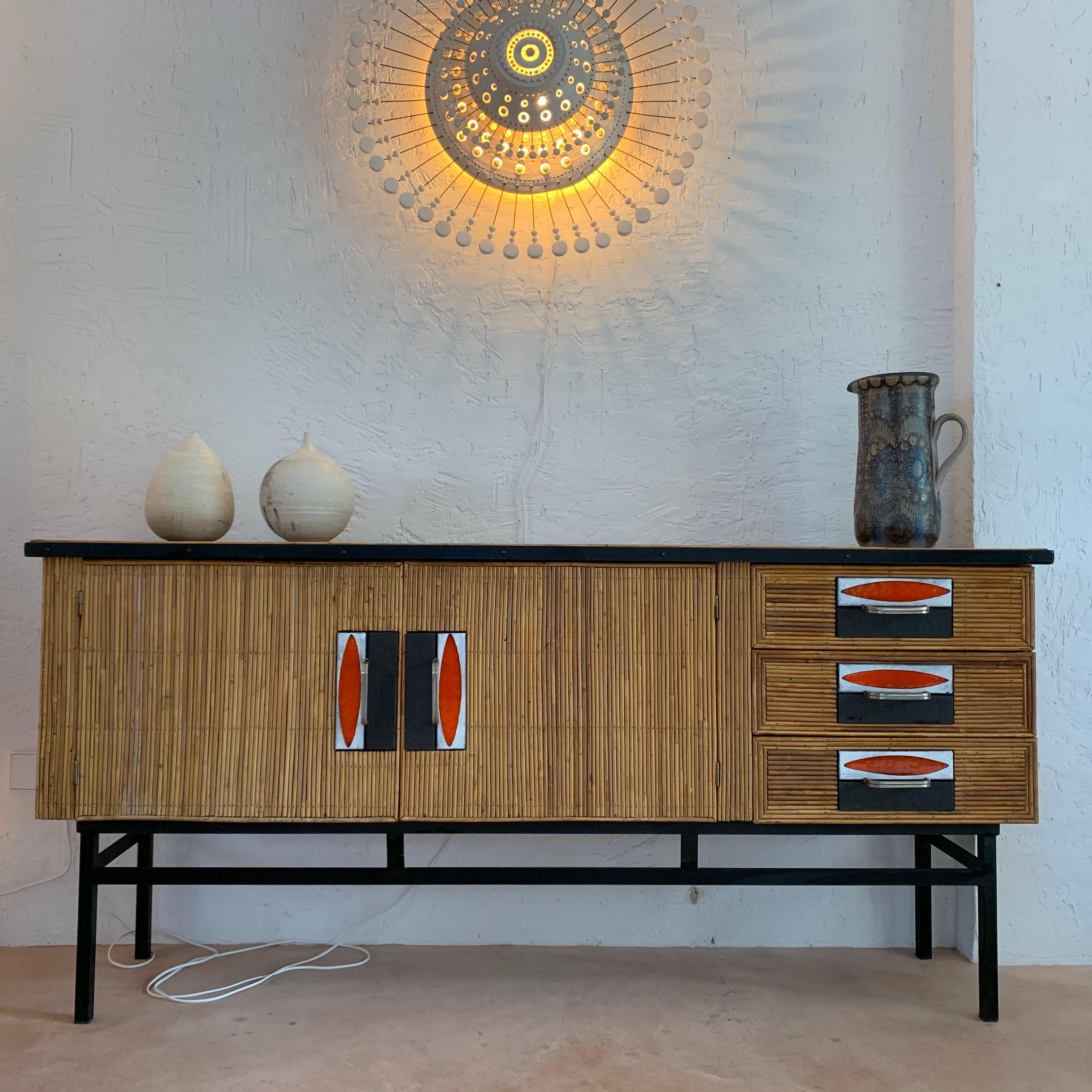 Rare sideboard with black lacquered metal legs and rattan frame. Three drawers decorated with polychrome glazed ceramic tiles called Navettes. Nickel-plated steel pull handles.
 