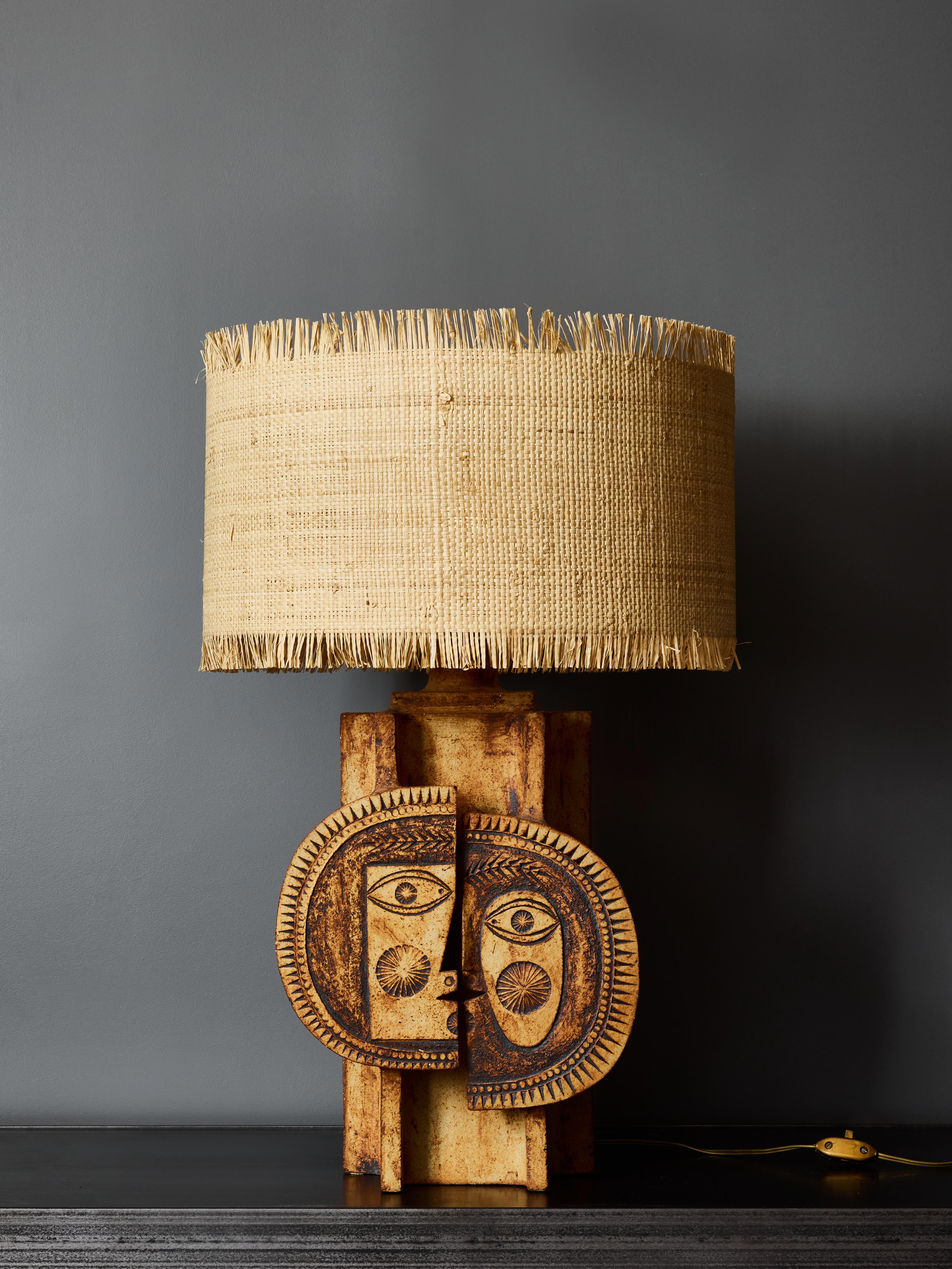 Questa splendida lampada da tavolo, disegnata da Roger Capron e Jean Derval, è realizzata in ceramica e presenta un sorprendente disegno centrale. A seconda della tua prospettiva, puoi vedere un unico volto diviso in due metà o due personaggi che si