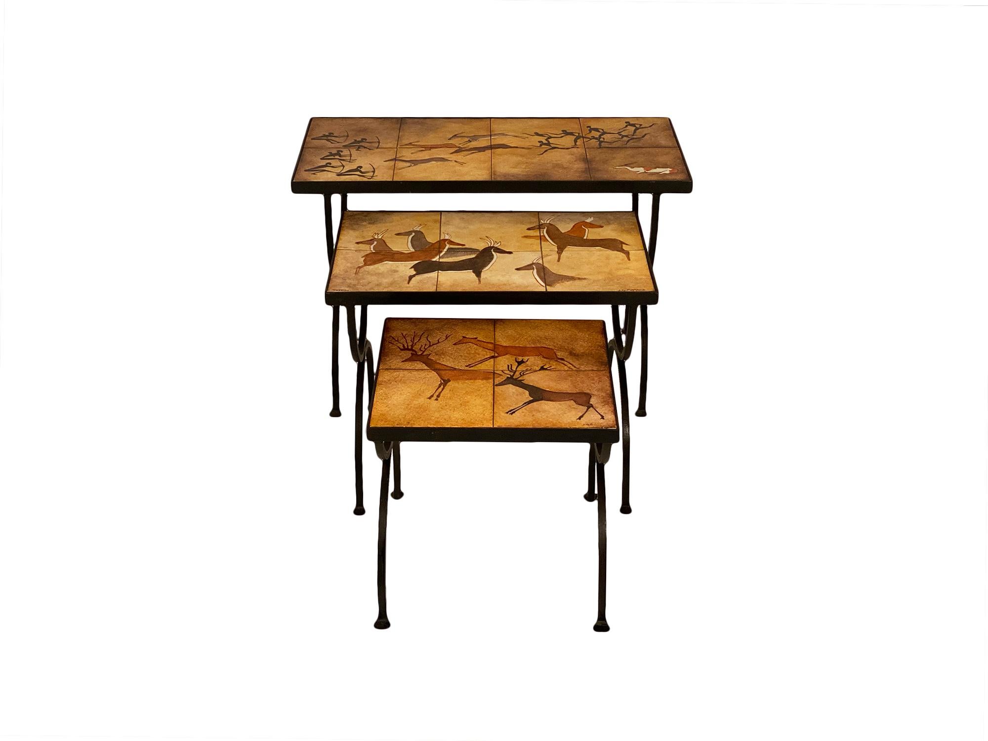 Set of nesting tables featuring a polychrome original work signed JG Flamand. The terracotta tiles that form the tops represent hunting scenes in a cave painting style. The bases are hand-hammered forged iron.
