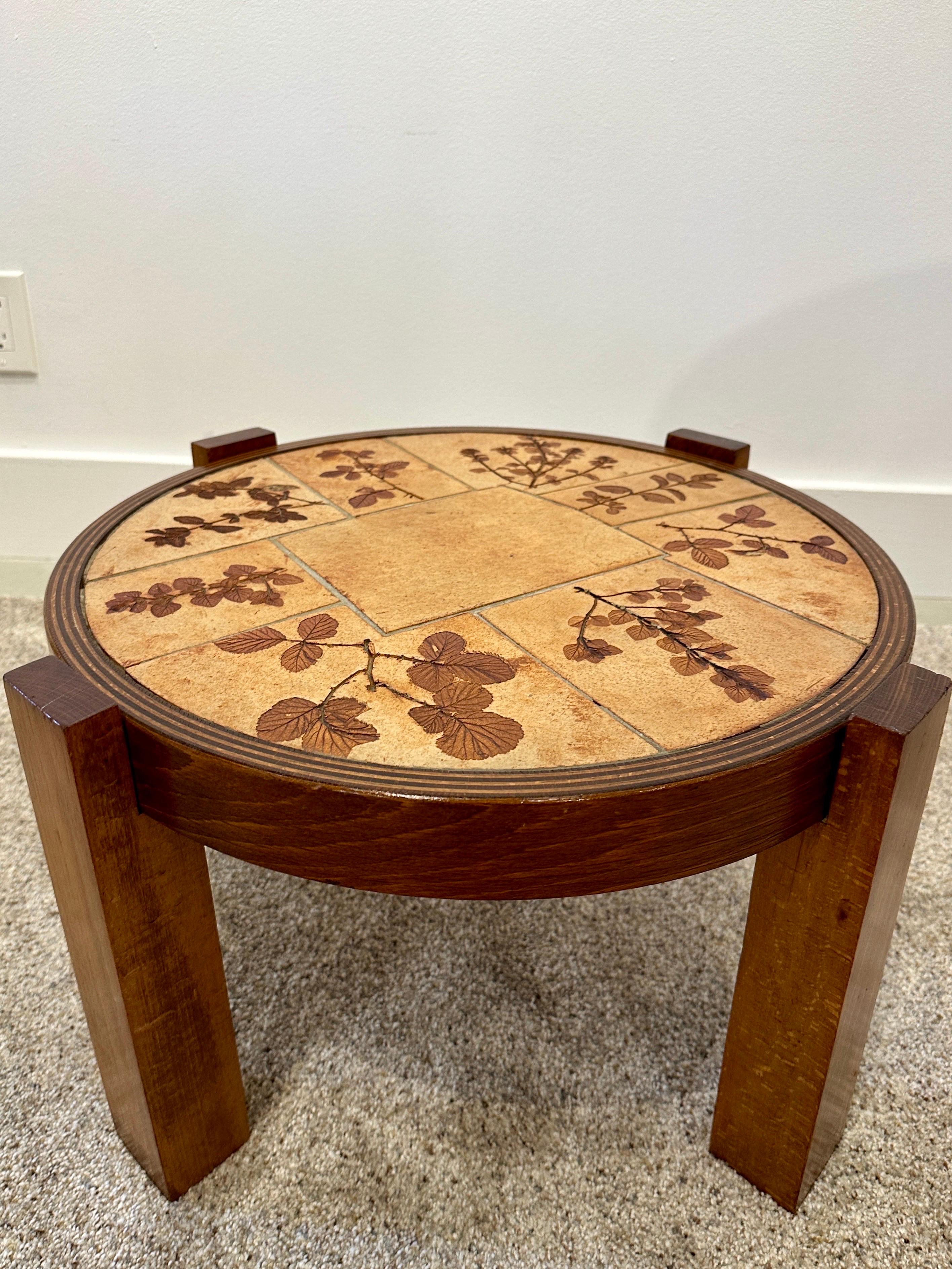 A  beautifully organic small scale round coffee/side table with a warm earth-tone ceramic top featuring pressed flowers embedded in to the ceramic plateau.  Natural oak wood base with simple ridges detailed around the top.  THIS ITEM IS LOCATED AND