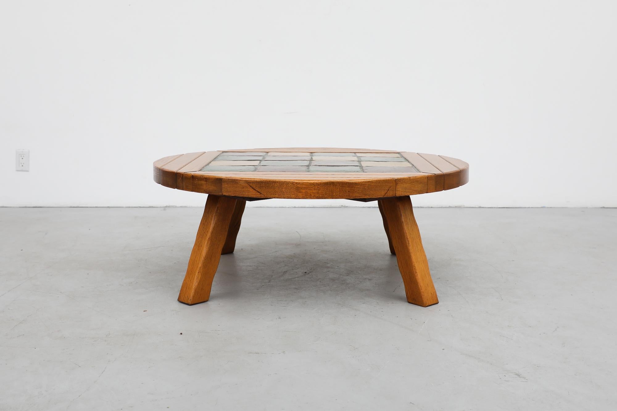 Midcentury round oak coffee table with inset glazed checkered tile top. In the style of Roger Capron and Tue Poulsen. The table is in original condition with visible wear consistent with its age and use.