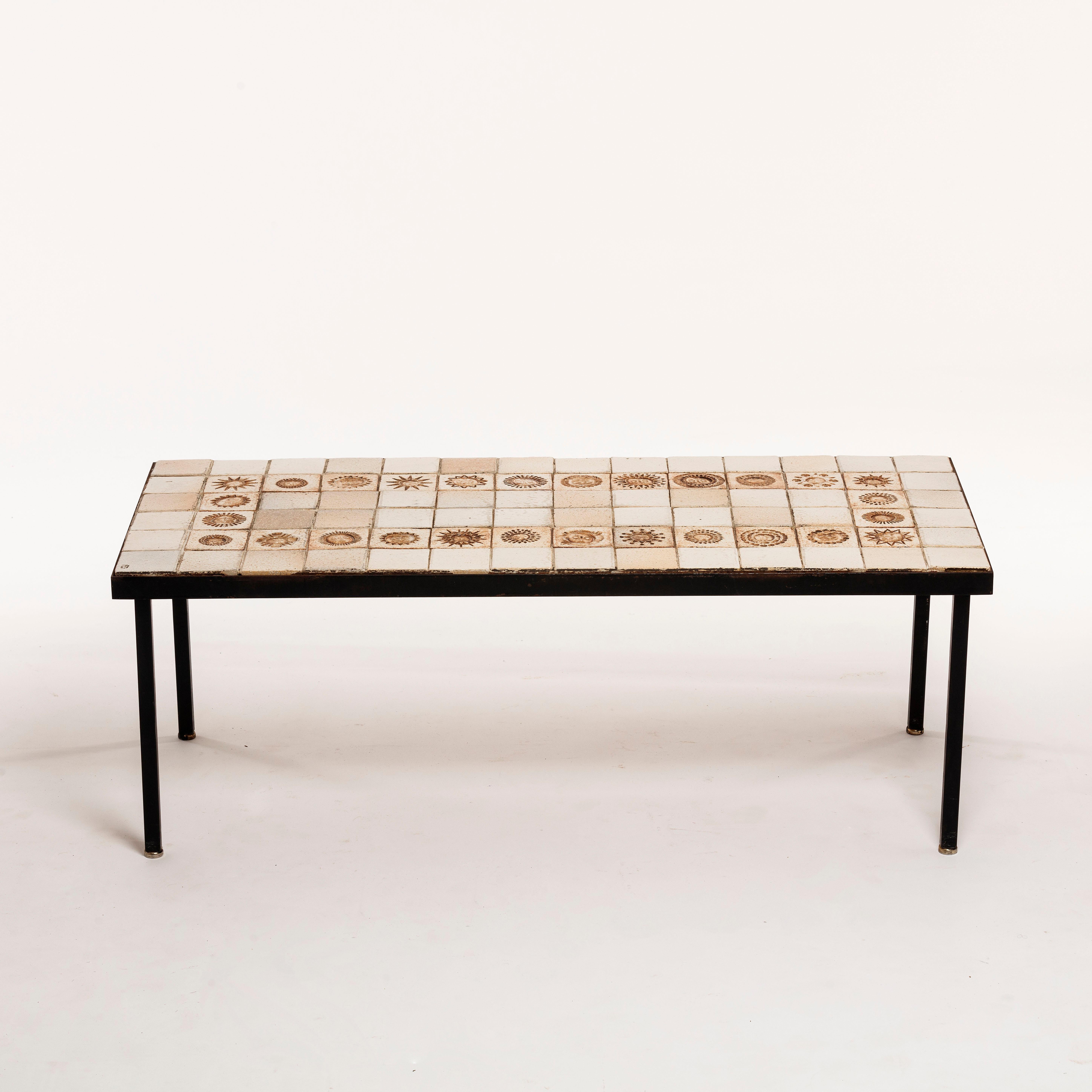 Très rare table basse en céramique du designer Roger Capron, années 1960. La structure est en métal noir et le dessus en variation blanche avec 26 petits soleils différents gravés sur des carreaux de céramique émaillée.

La table est signée et en