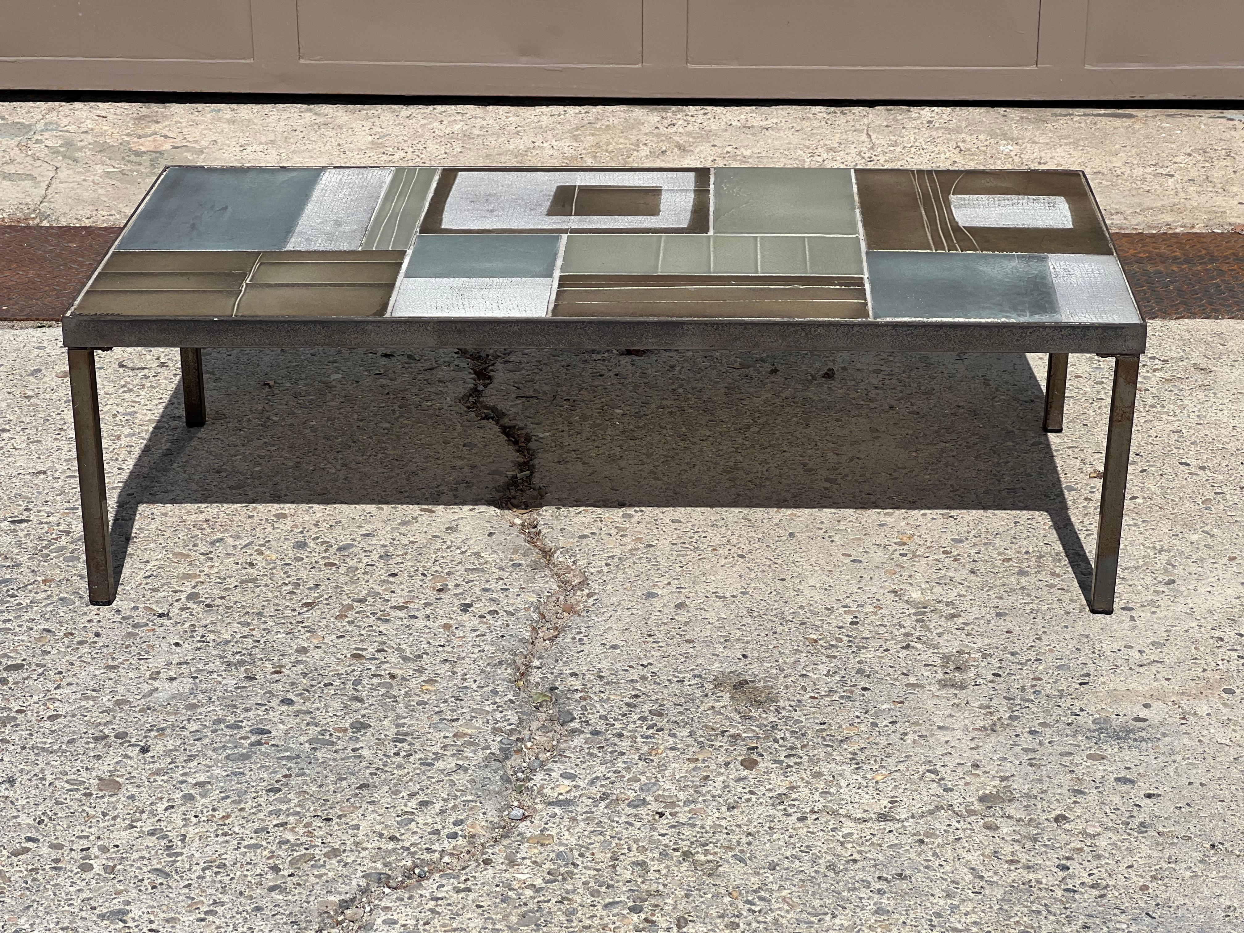 Roger Capron 1960 coffee table. Ceramic top in shades of blue and gray with geometric patterns. Black wrought iron base. Signature on the top.
Good condition