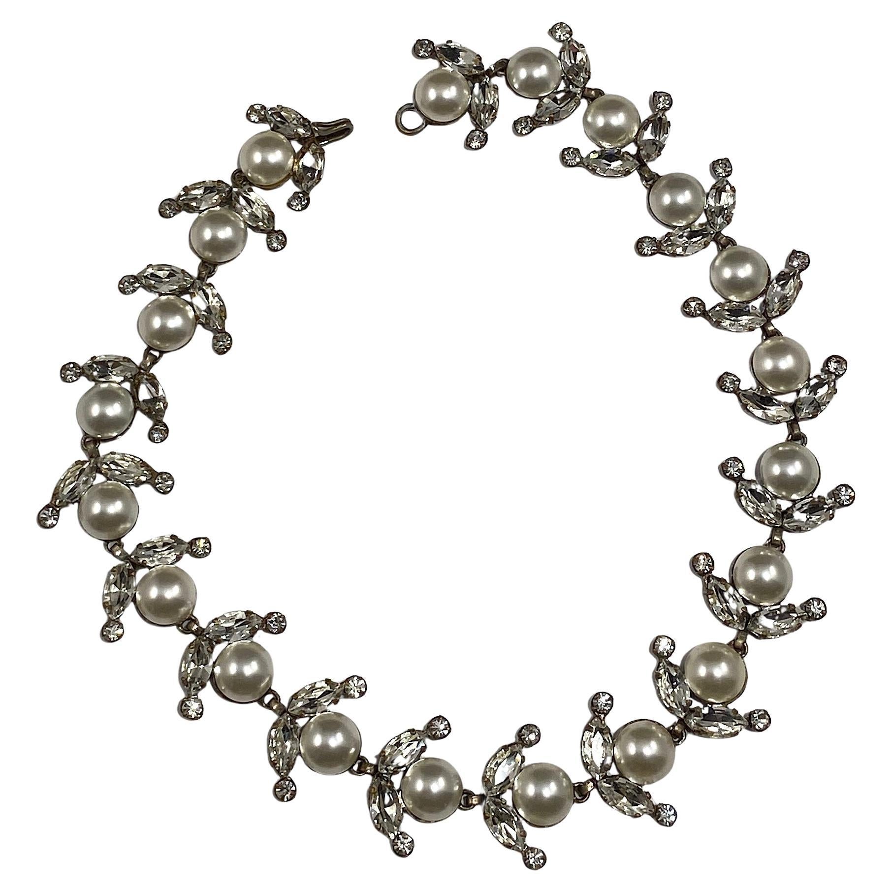 Collier classique et féminin en cabochon de perle de verre et strass clair par Roger Jean Pierre des années 1950. Pour Christian Dior.


Montés dans des montures en métal argenté, les maillons articulés sur une seule rangée sont chacun sertis d'un