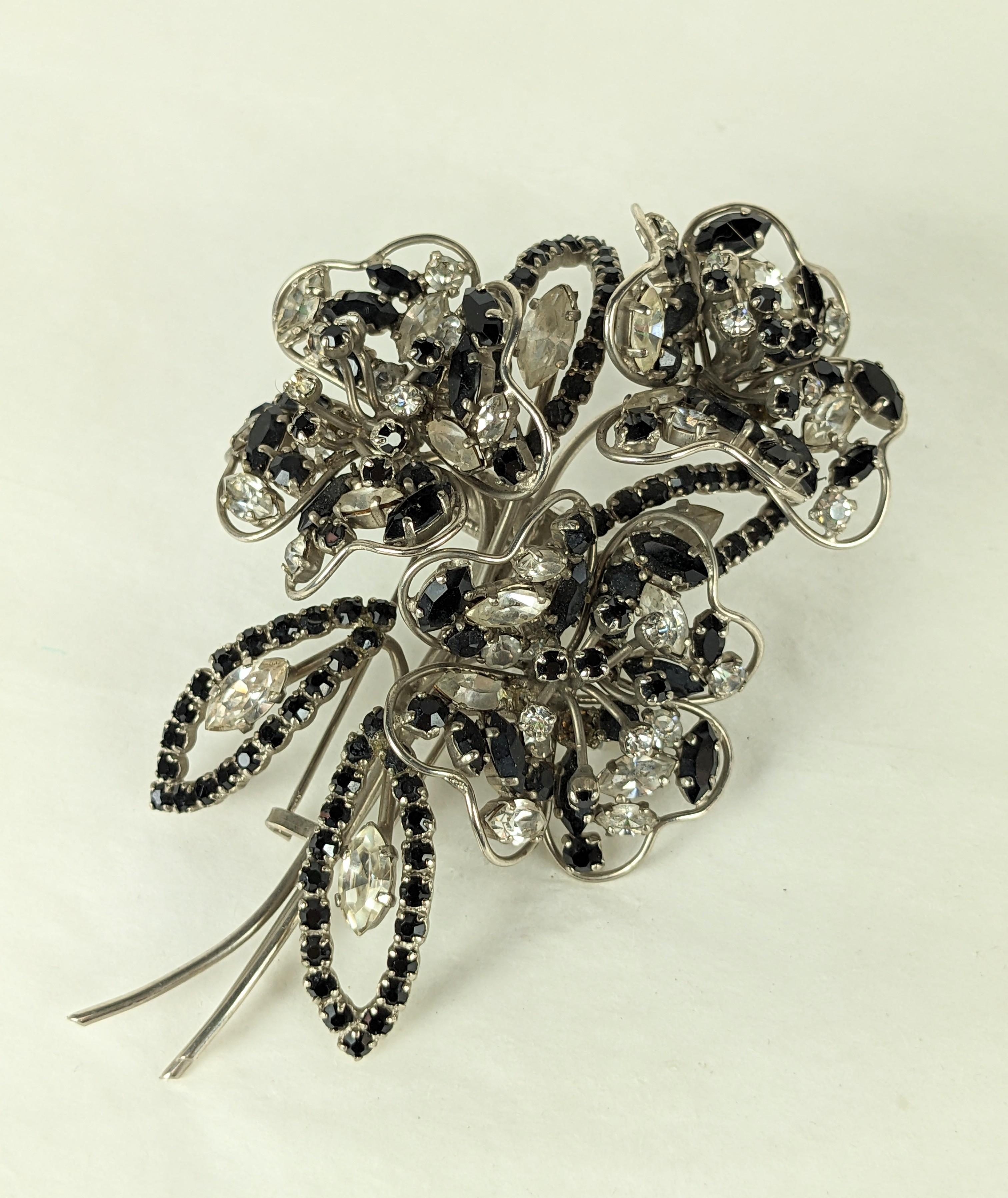 Roger Jean Pierre großformatige Depose-Bouquet-Brosche aus den 1950er Jahren. Die dreidimensionale versilberte Drahtarbeit  Die Brosche besteht aus drei Blumen in Kristall und Jet mit runden und marquisen Steinen. Zusätzlich verziert mit vier Jet-