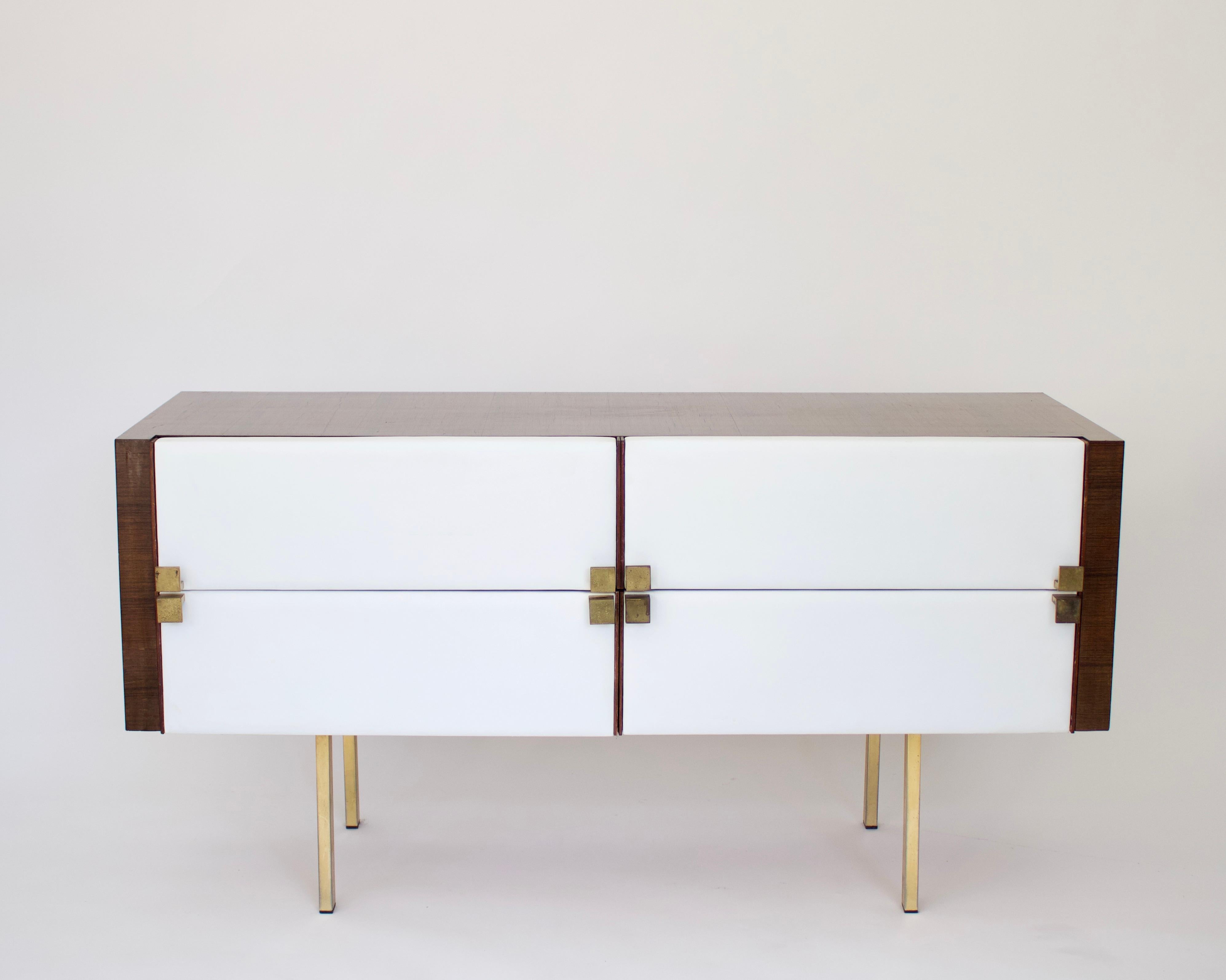 A French modernist cabinet vanity dresser or dressing table by Roger Landault featuring a body in mahogany with brass legs and bronze pulls with upholstered fronts done in a white leather.
The cabinet also features three drawers as well as one faux