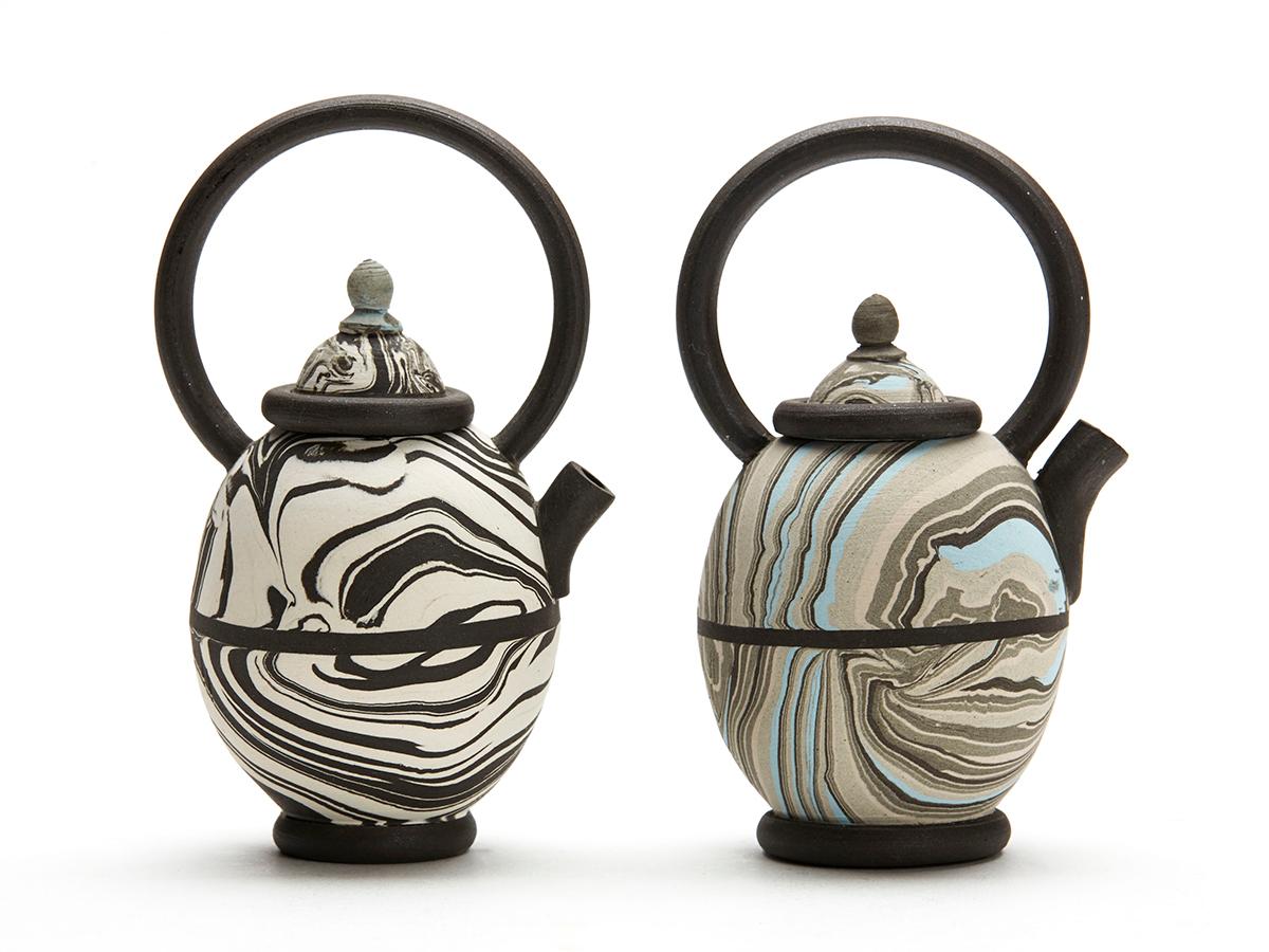 A stylish pair vintage miniature studio pottery marbled clay teapots of egg shape with tall loop kettle style handles by Roger Michell and dated 1984. The teapots are press molded with marbled clay, this is colored clay pressed and rolled together