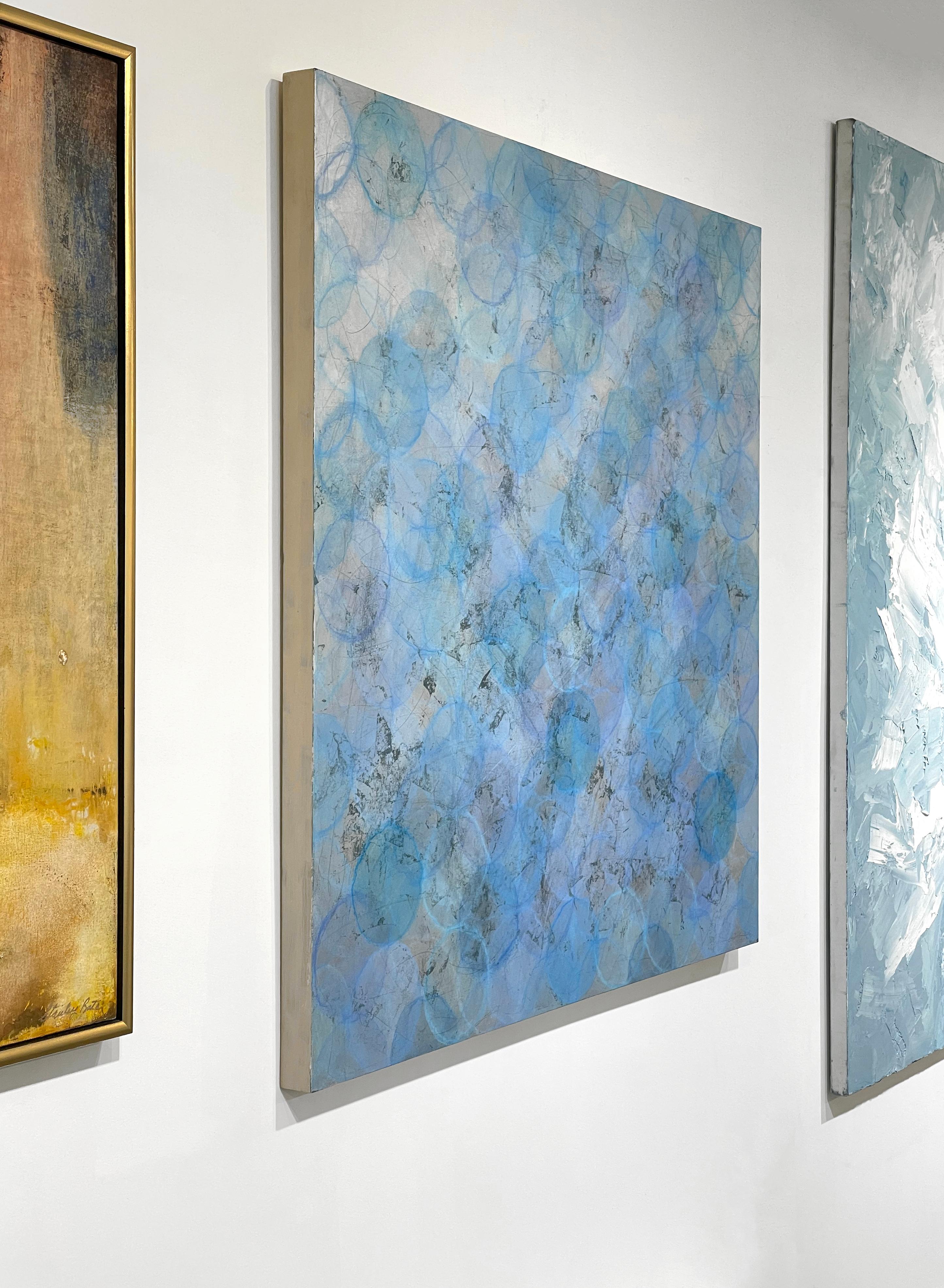 Questo quadro astratto di Roger Mudre è realizzato con pittura acrilica su foglia di metallo su pannello. Il dipinto è caratterizzato da una tavolozza di colori blu chiaro e argento metallico, con caldi e sottili tocchi di lavanda stratificati.